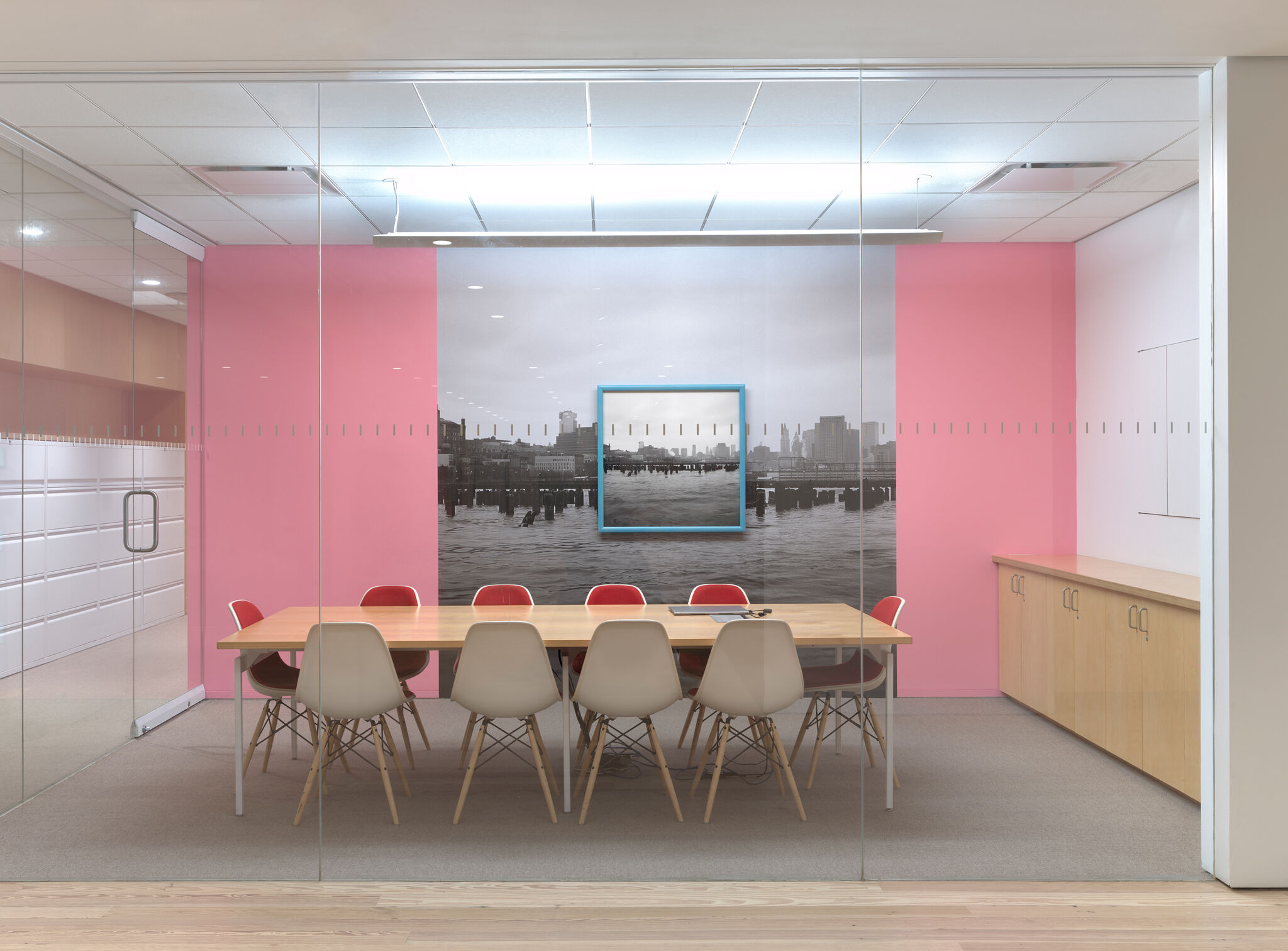 Black and white photographs on a pink wall in a conference room.
