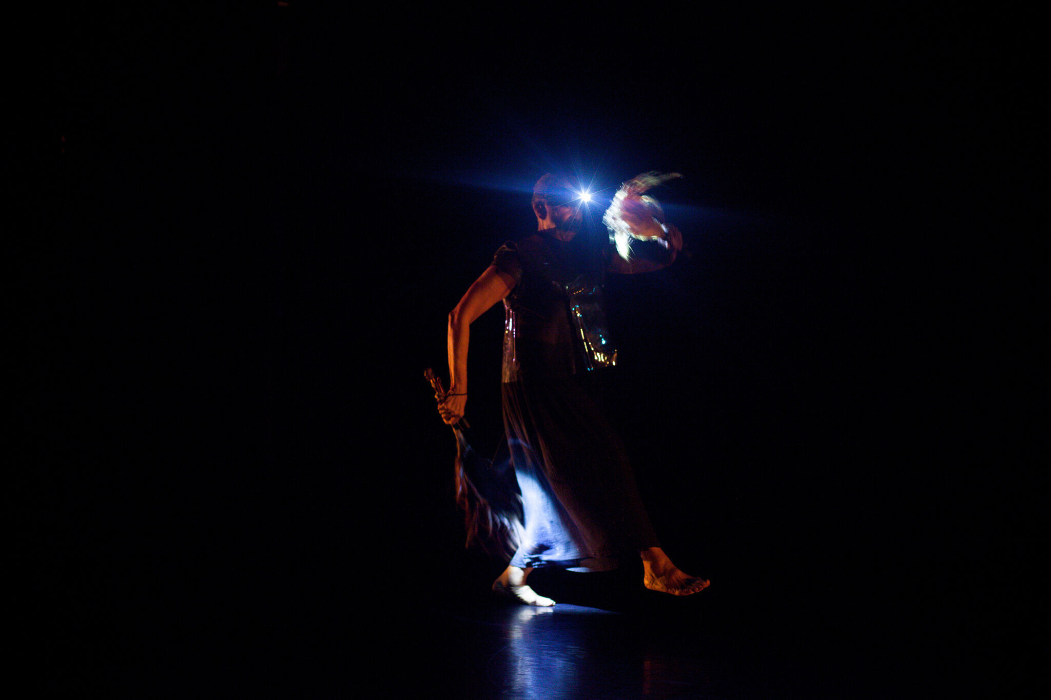 Person dancing and carrying props in a dark room. 