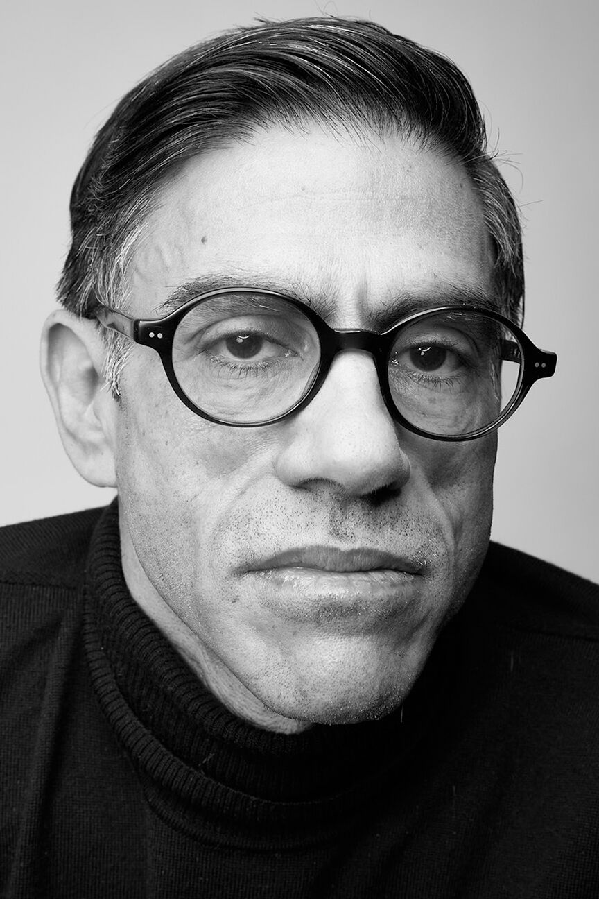 Headshot of Gregg Bordowitz in black and white wearing a dark sweater and rimmed glasses.