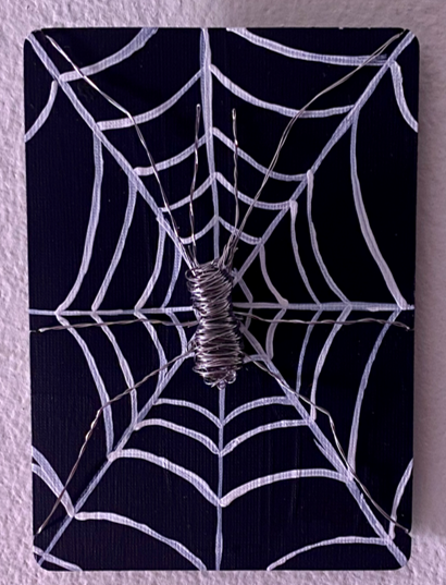 A metal spider on a drawn spider web.