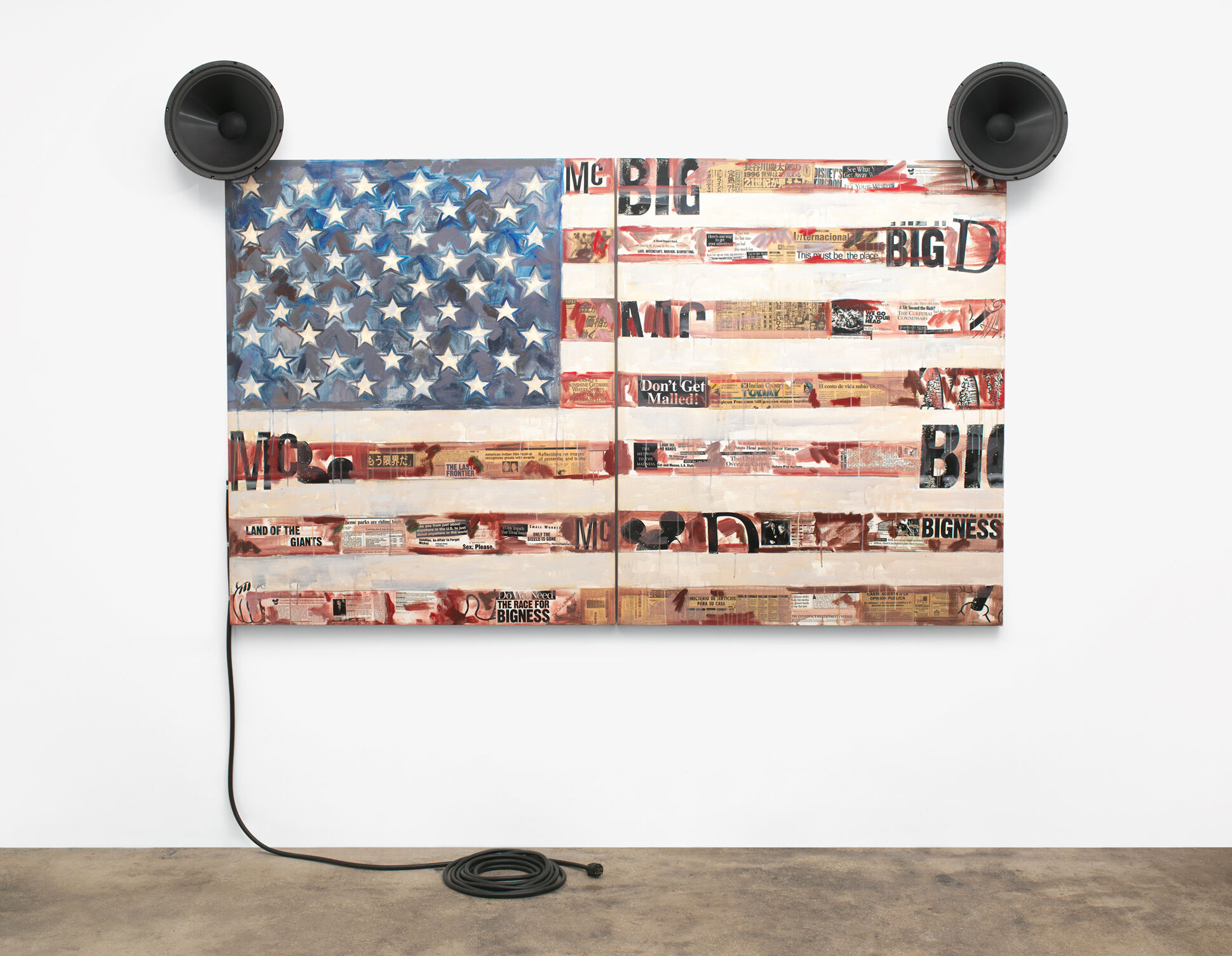 A painted and collaged flag with circular sound systems at the top corners that resemble Mickey Mouse ears. 