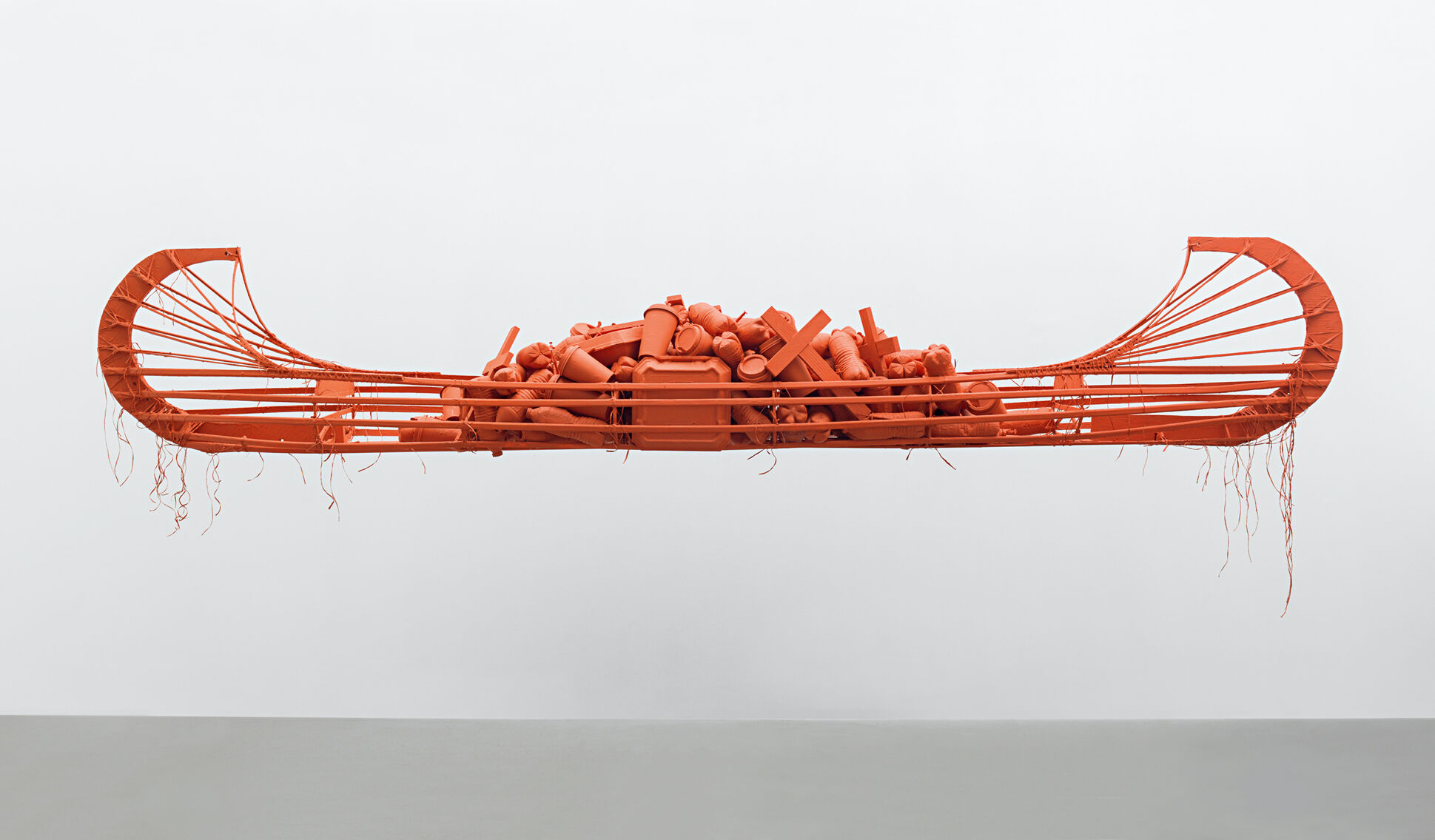 A monochromatic red canoe floating in space and laden with a heap of garbage. 
