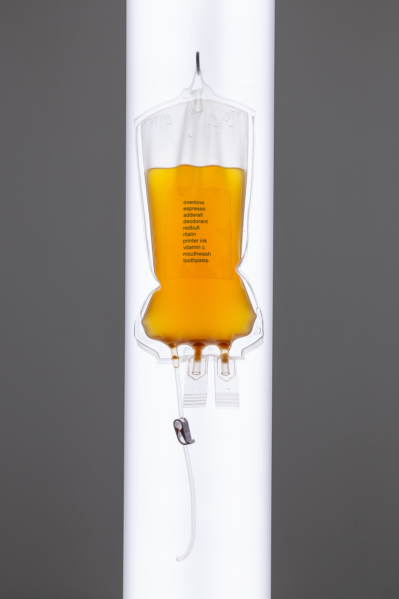 An IV drip bag filled with orange liquid and words written on the front. 