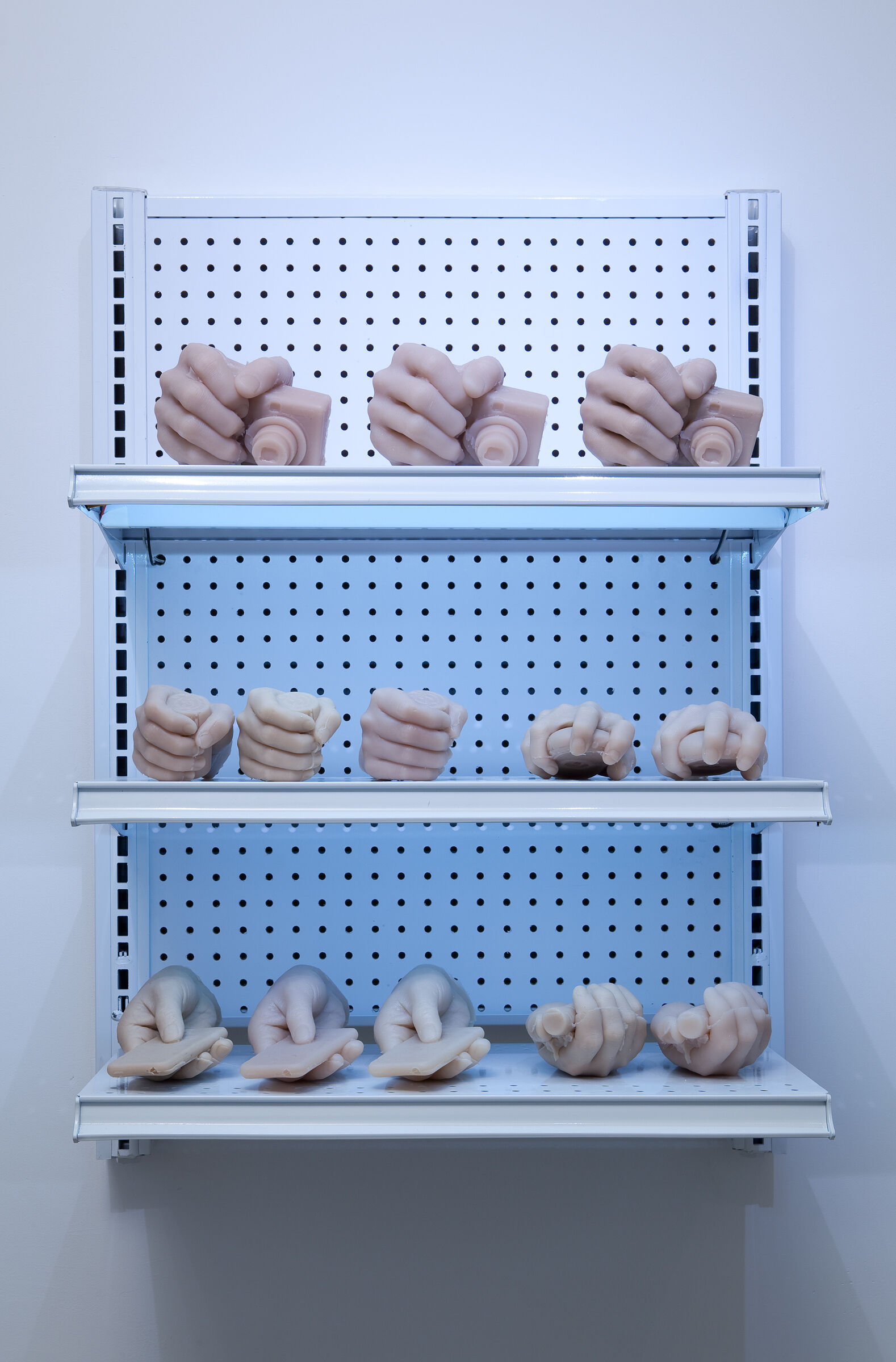 A shelf laden with sculptures of hands holding different items. 