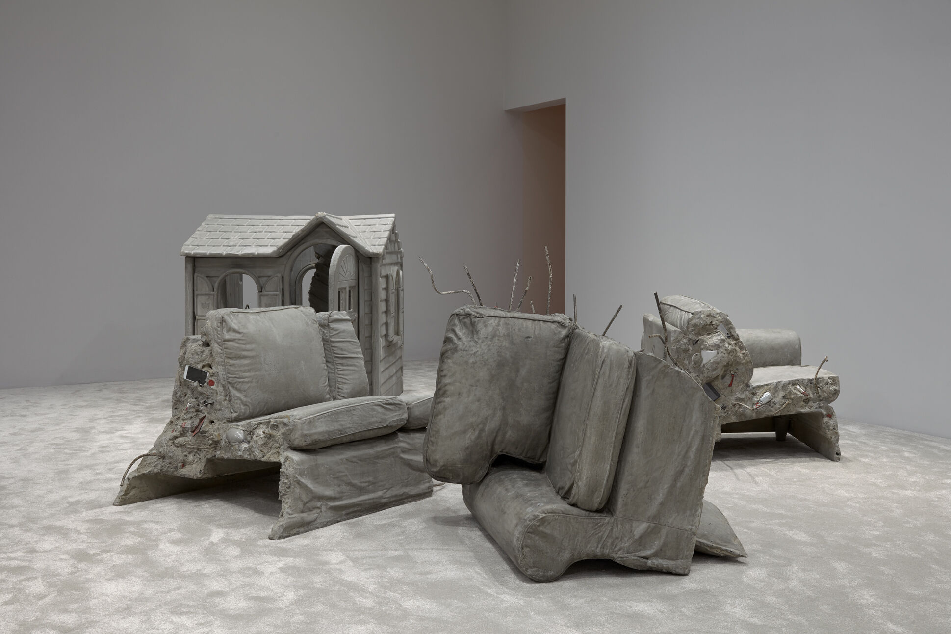 Crumbling casts of furniture made of what looks like concrete as well as the cast of a play house. 
