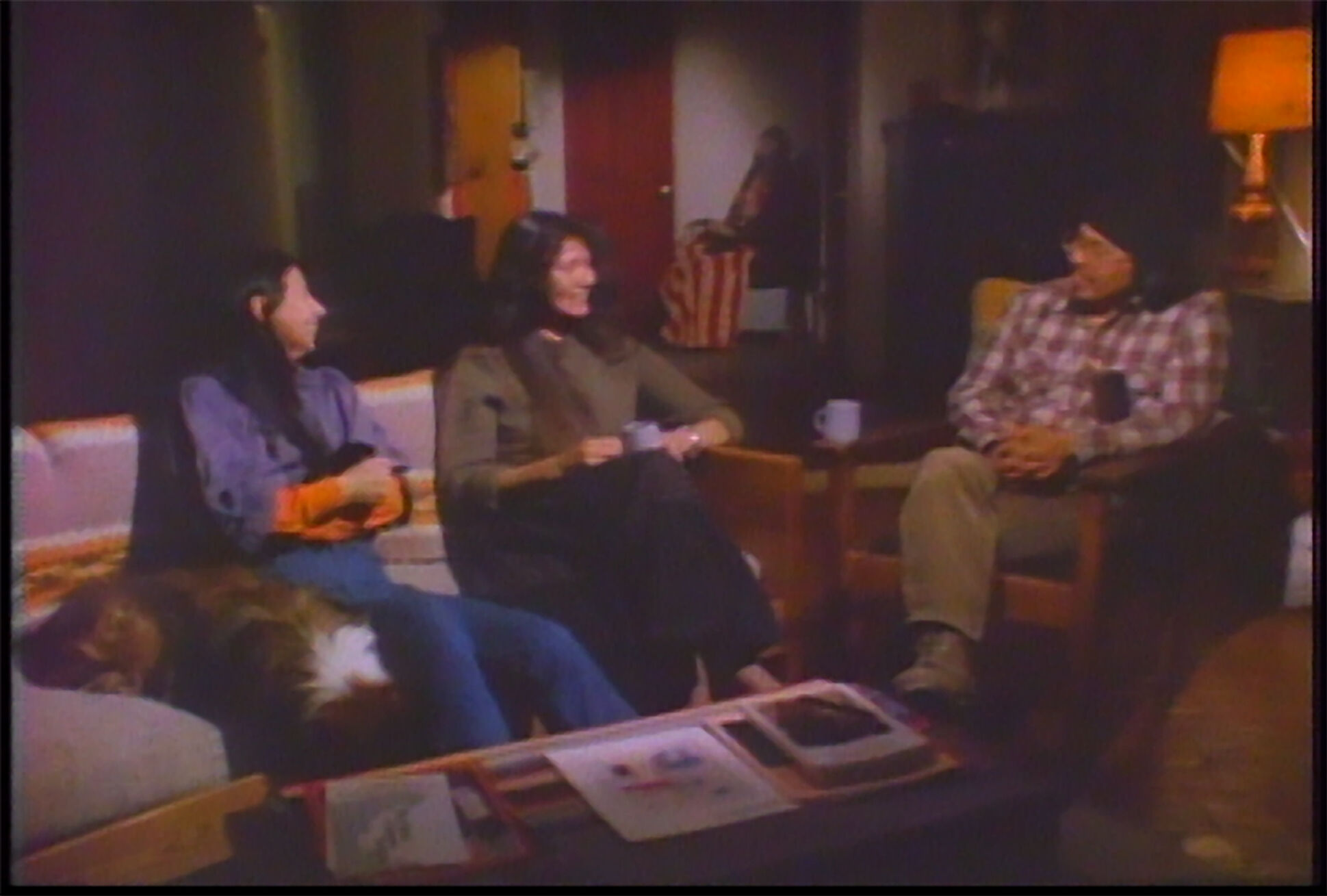 Three people sit around a coffee table in a living room. 