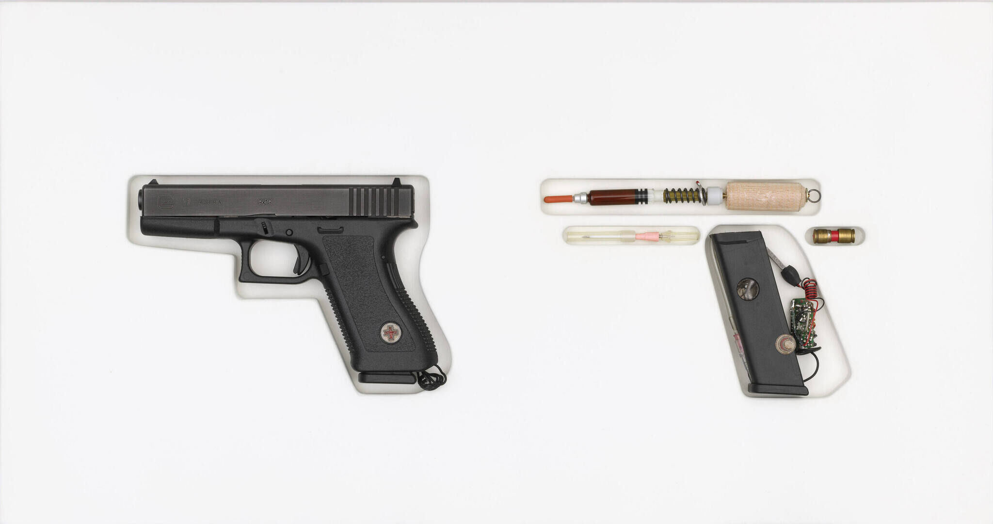 A handgun rests next to medical supplies arranged in the shape of a handgun.