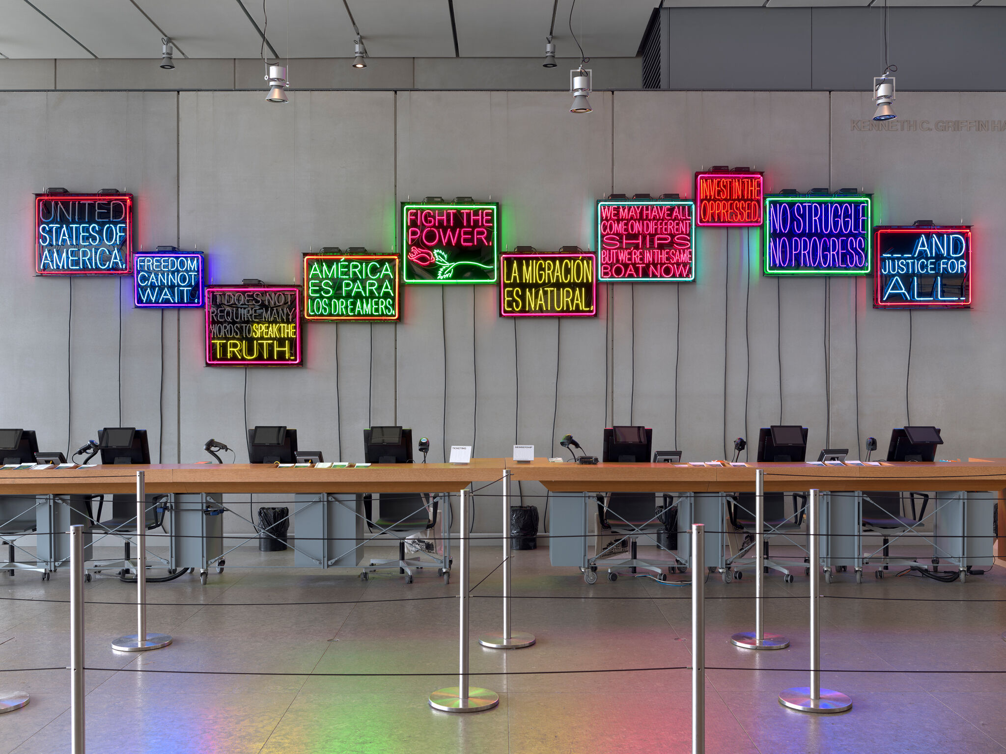 The admission counter at the Whitney Museum of American Art with an neon light installation behind. 