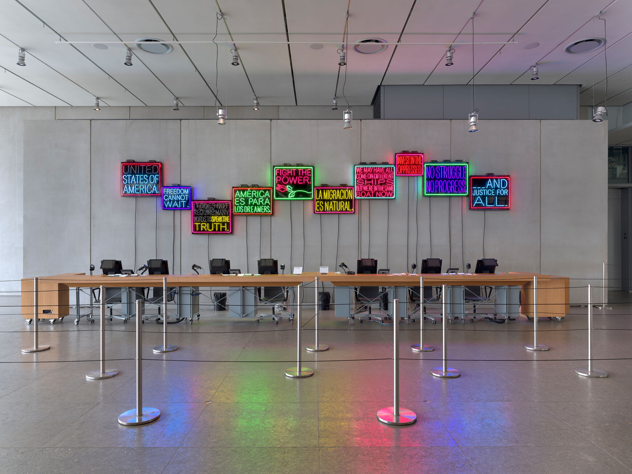 The admission counter at the Whitney Museum of American Art with an neon light installation behind. 