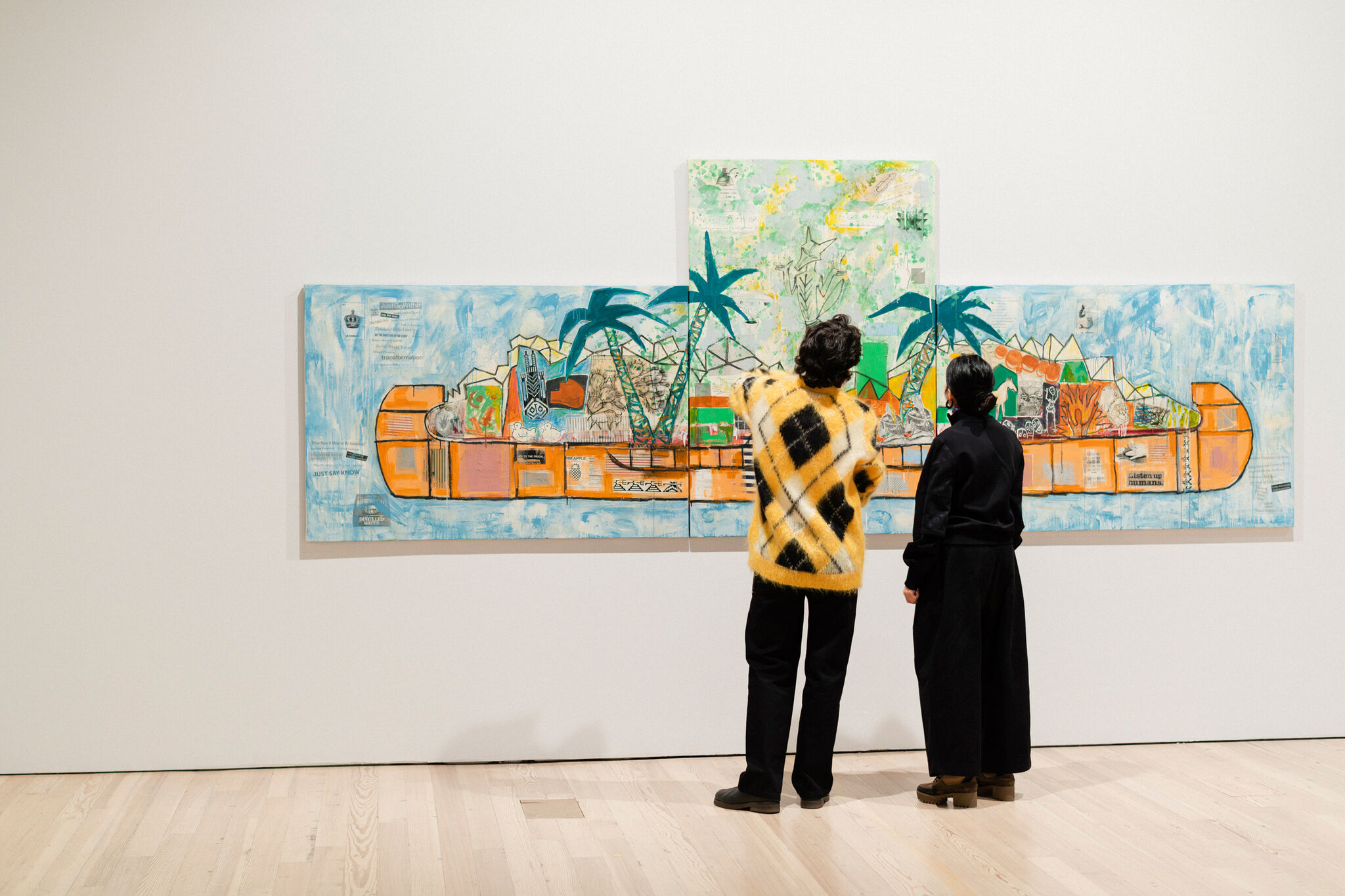 Two people in a gallery looking at a painting of a canoe with palm trees and many beings and objects within it. 