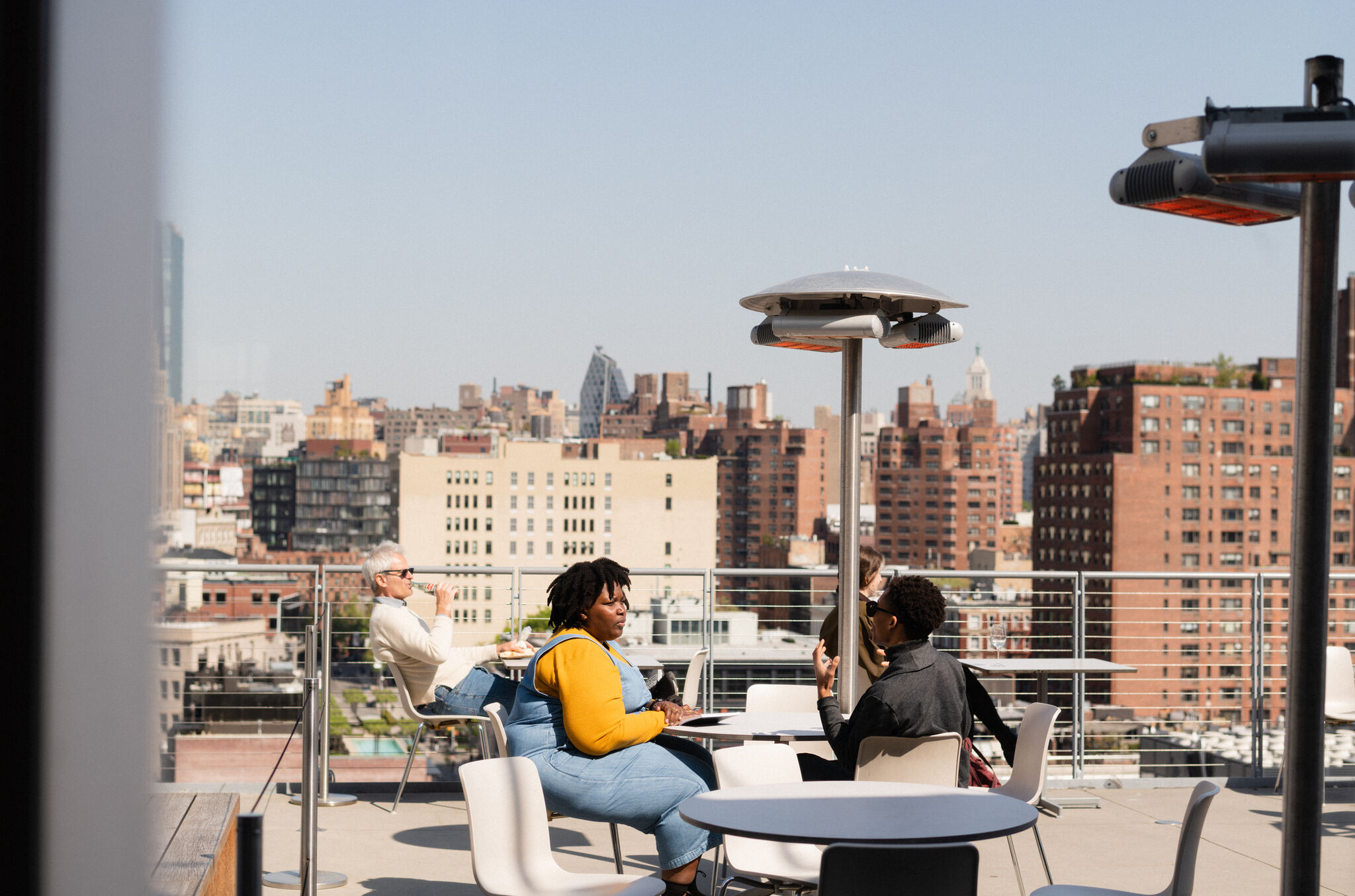 A view of two people dining on the terrace and a city view on a sunny day.