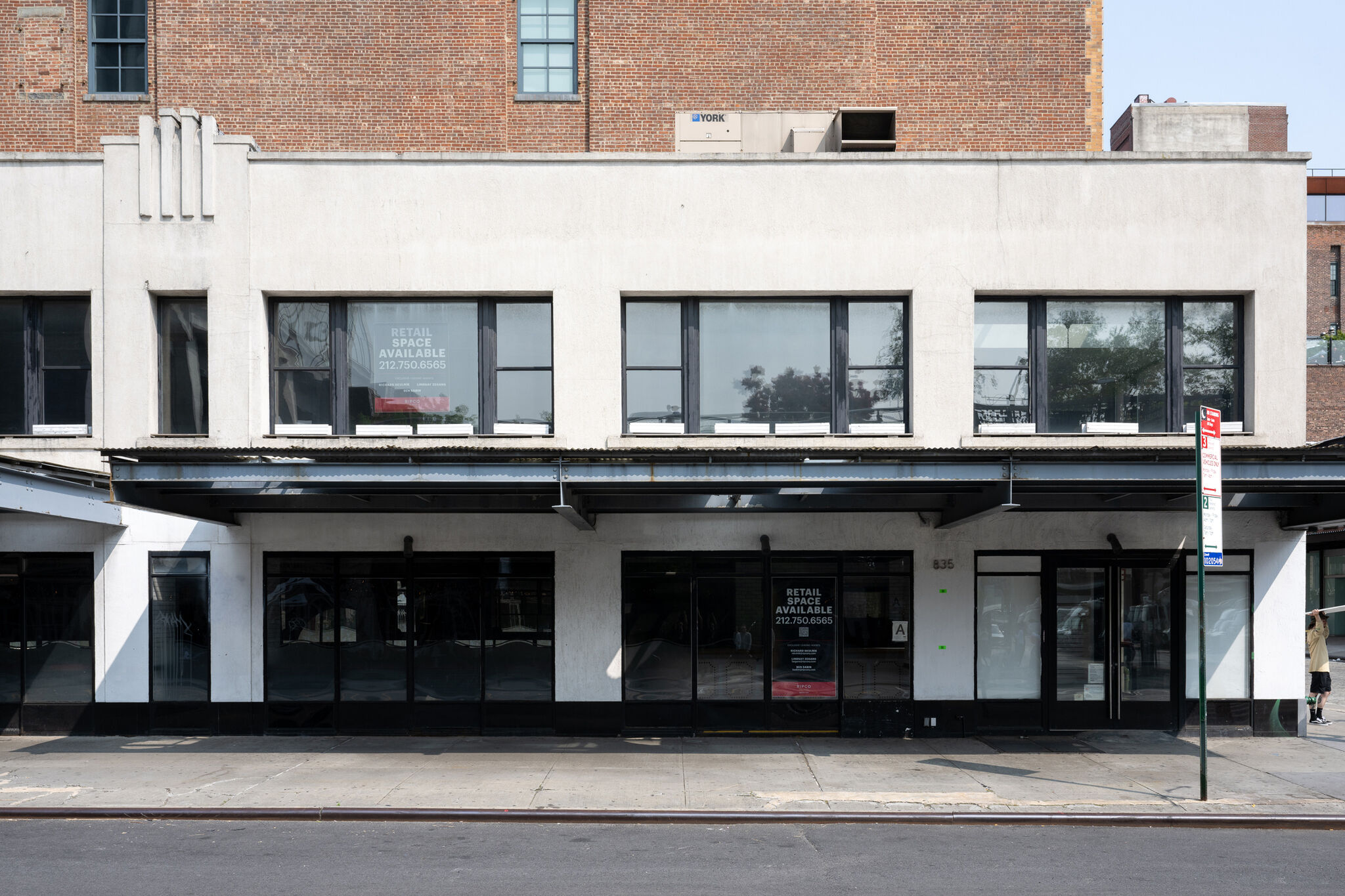 A two story white building with a large black overhang. 