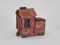 A little brown house sculpture made of wood and tin.