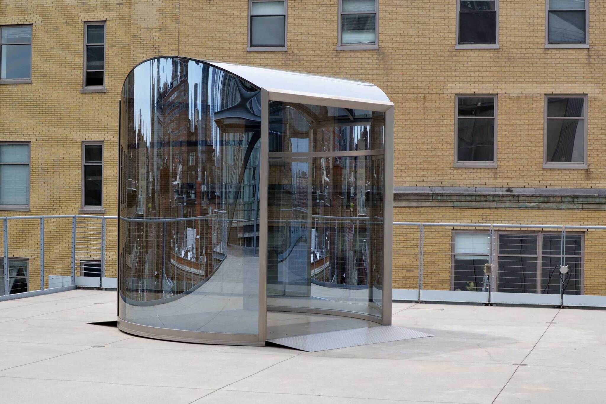 A clear room on a balcony made of glass and stainless steel.