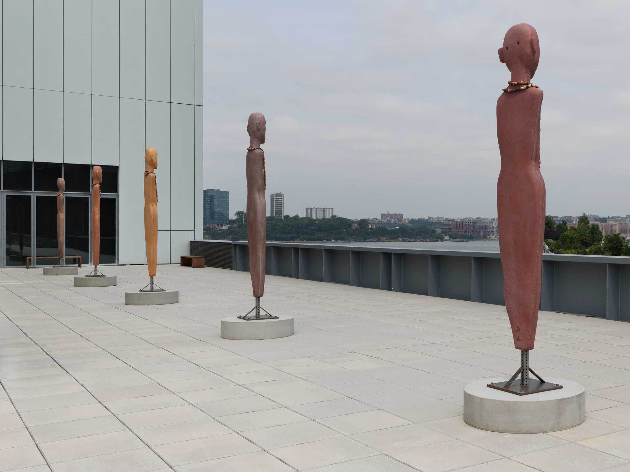 Tall human figure sculptures with no limbs stand straight on the balcony.