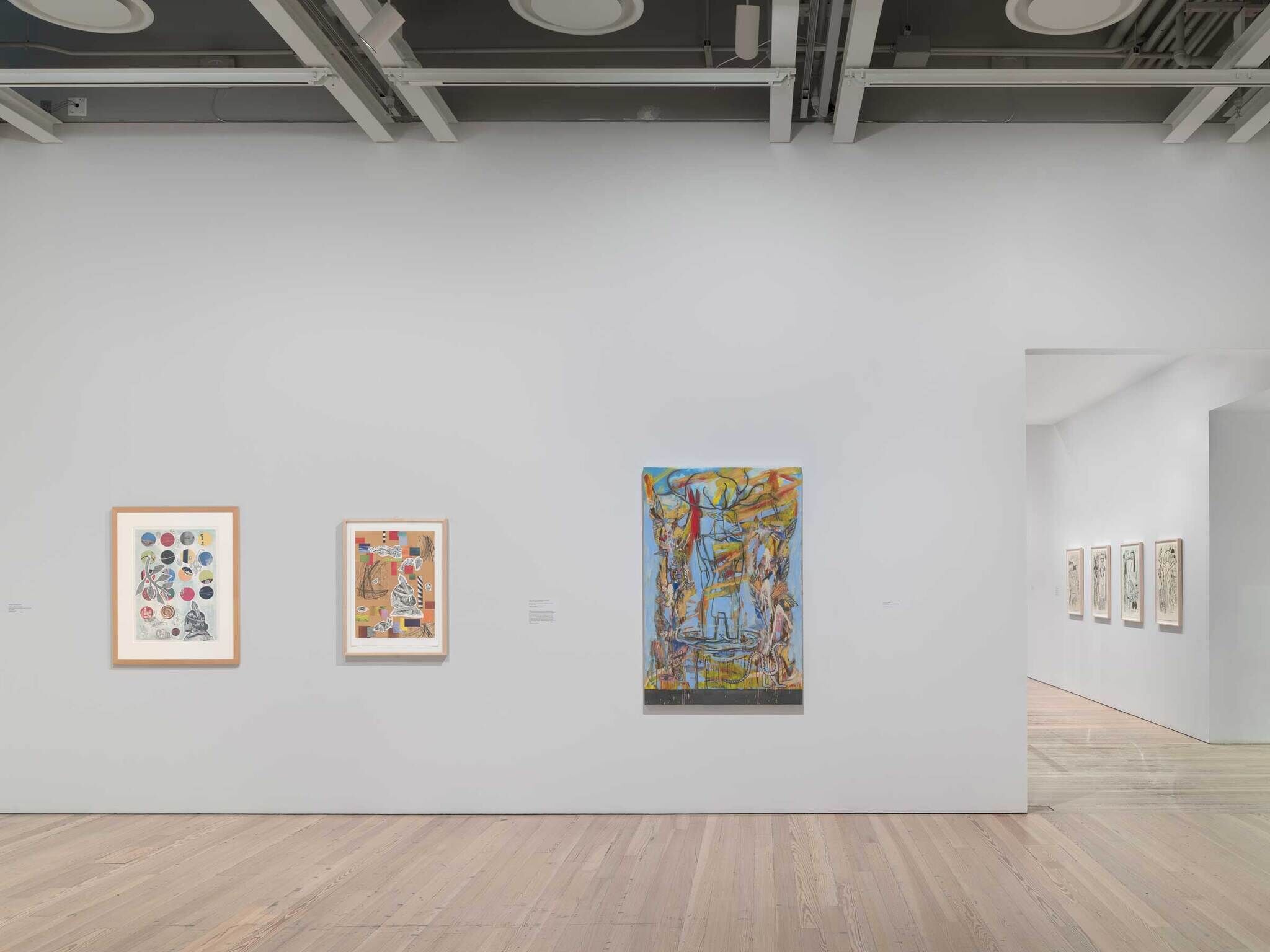 From left to right: a painting with colorful abstract circles, a painting with abstract shapes, and a colorful painting of a human figure with a deer head.