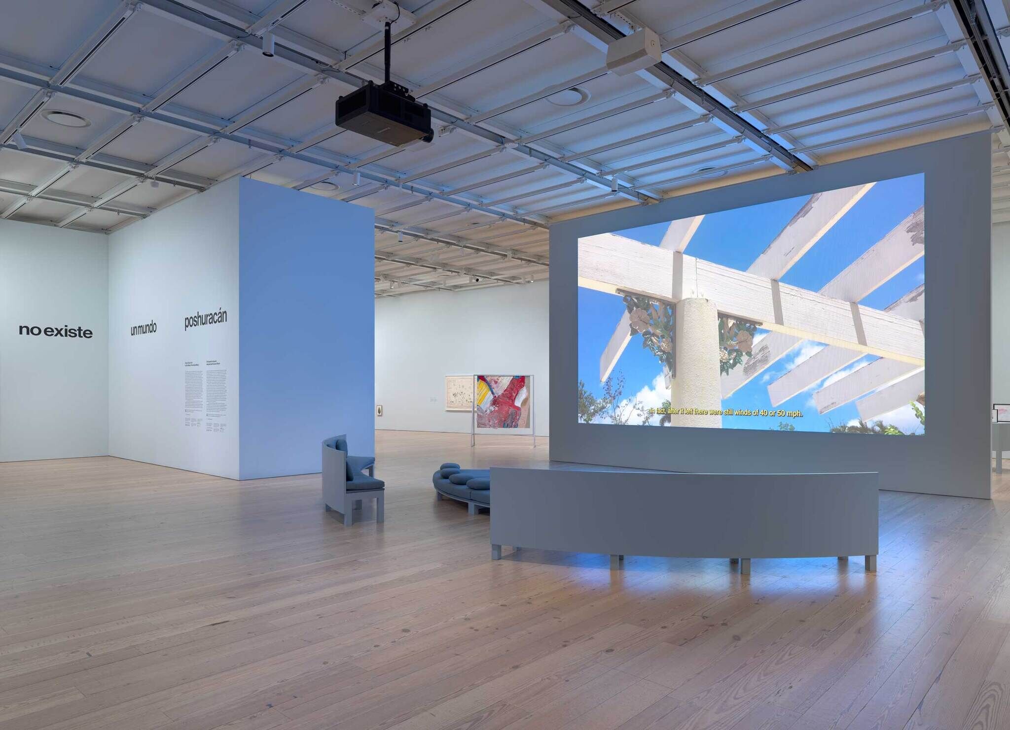 A big projection of an open roof with a blue sky in a room with three couches facing it.