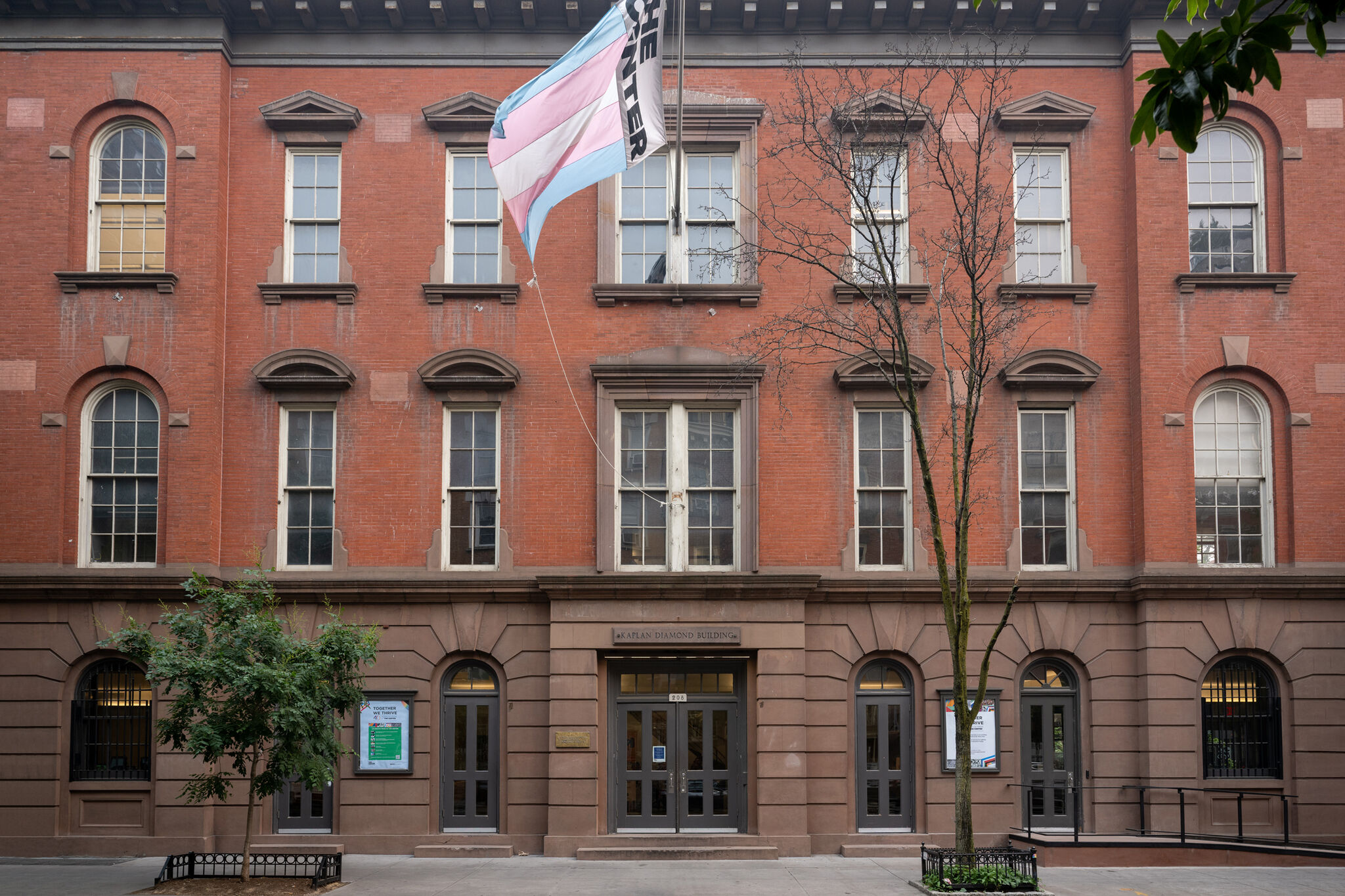 A three-story brick building with many windows and a flag billowing. 