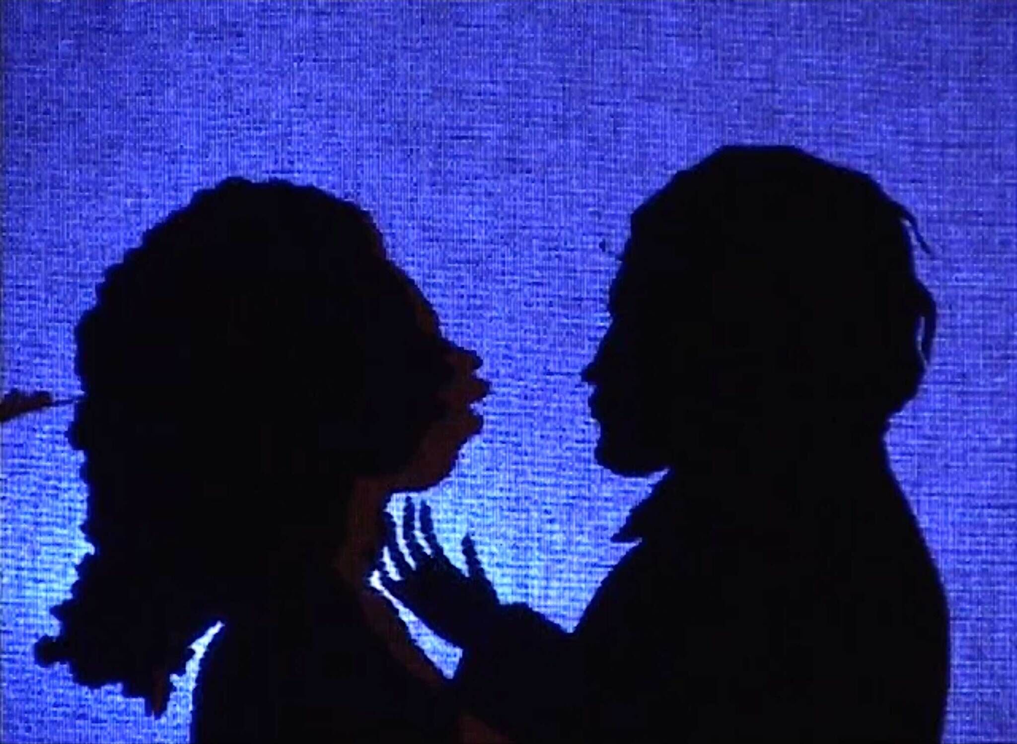 Two dark silhouettes against a blue background.