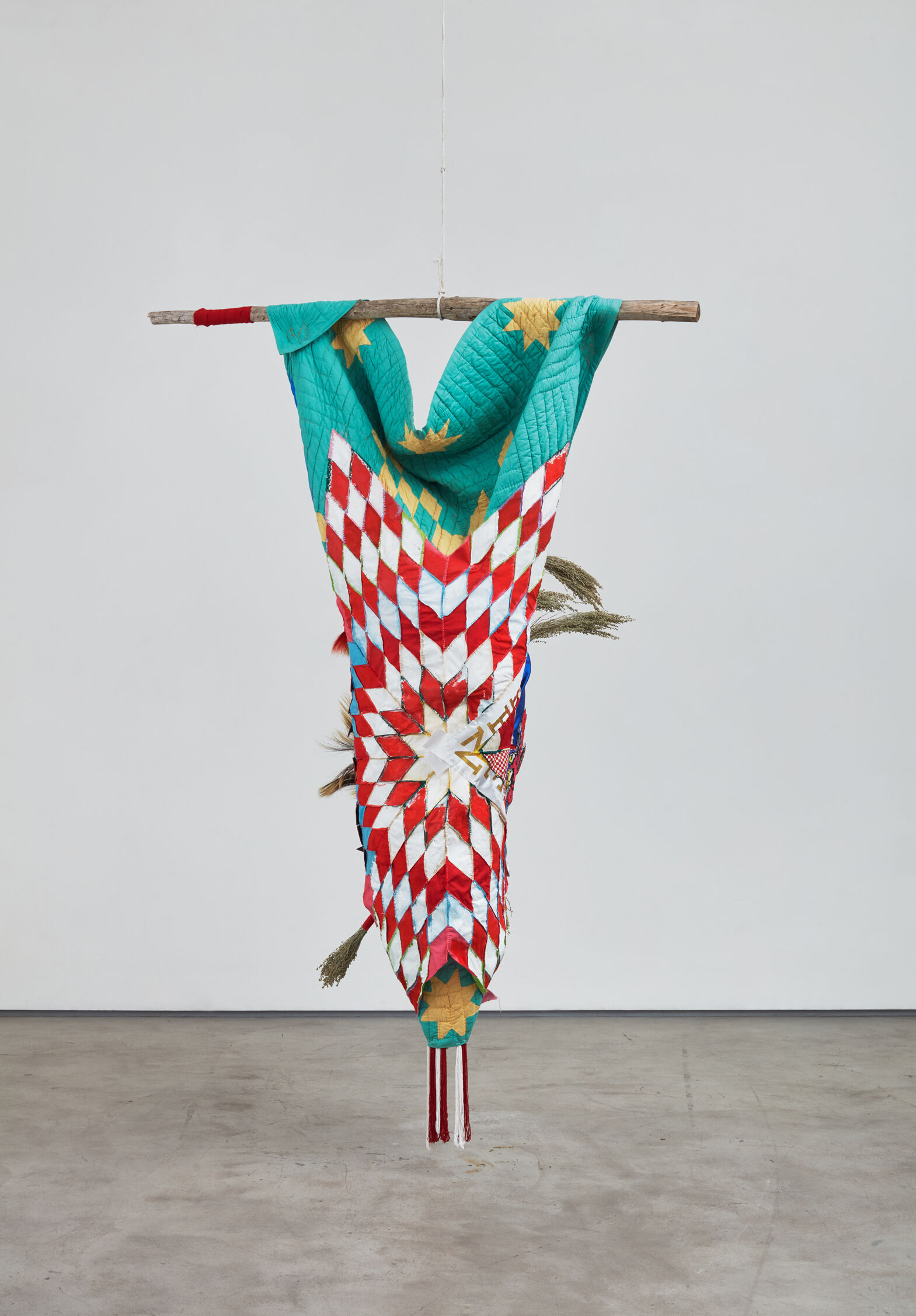 Bright textiles and materials are draped over wooden support and hung from the ceiling.