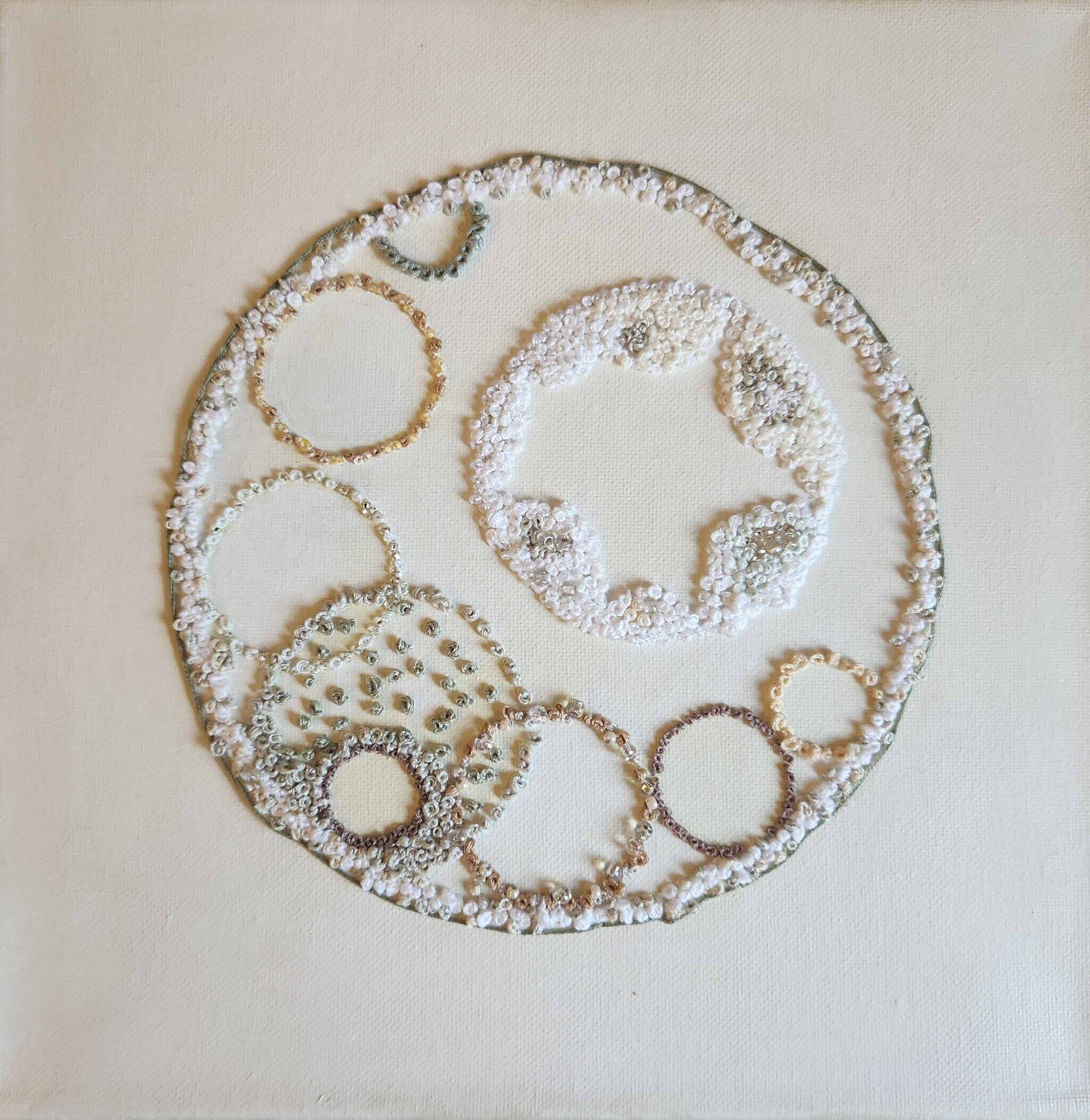 Pearls embroidered onto white fabric in circular shapes.