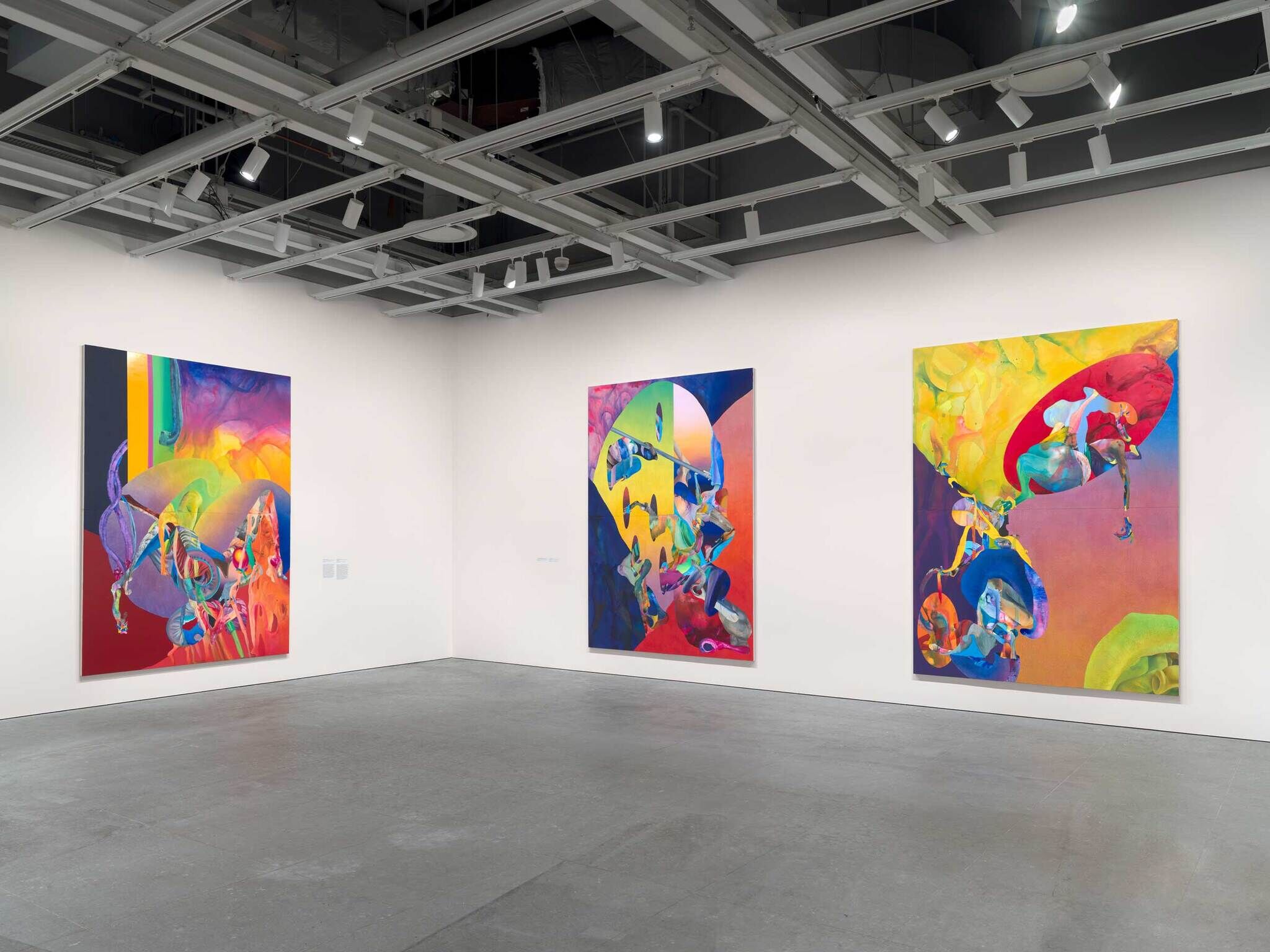 On the left wall, a big, vivid, and abstract painting, on the right wall, two of the big, vivid abstract paintings with different shapes and colors.