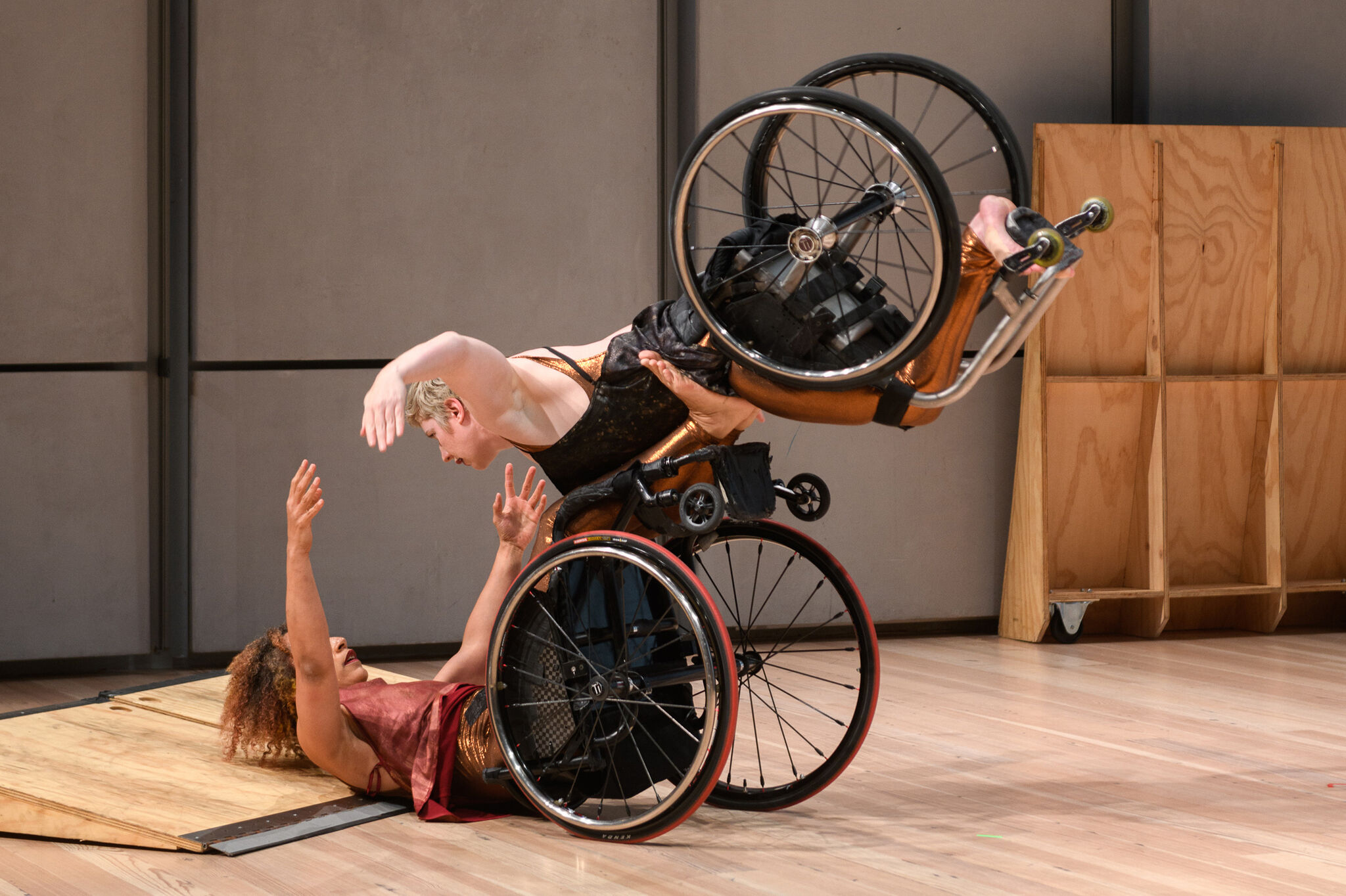 Two people in wheelchairs dance, one lifted into the air. 