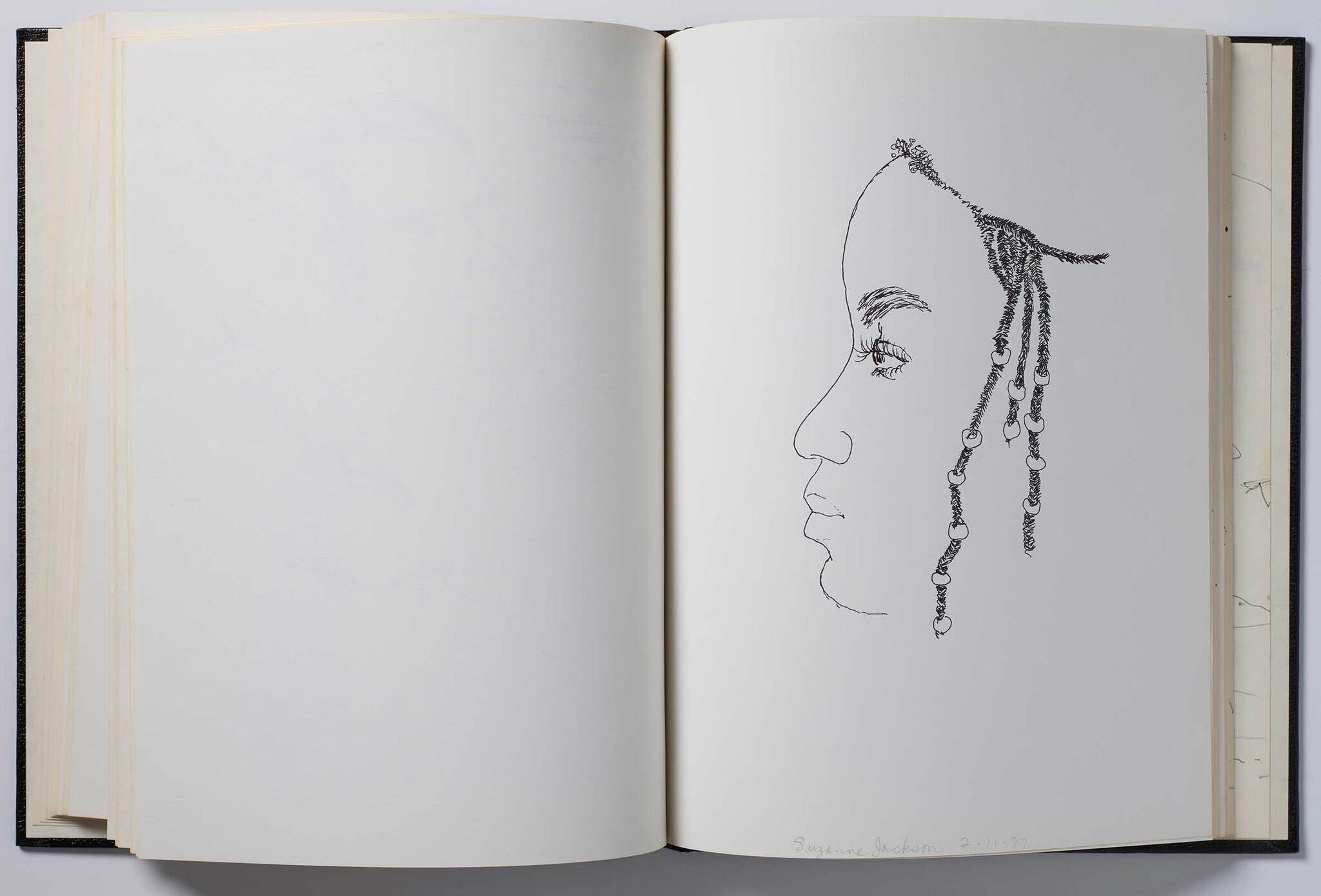 An open notebook with a drawing of a woman's face in profile.