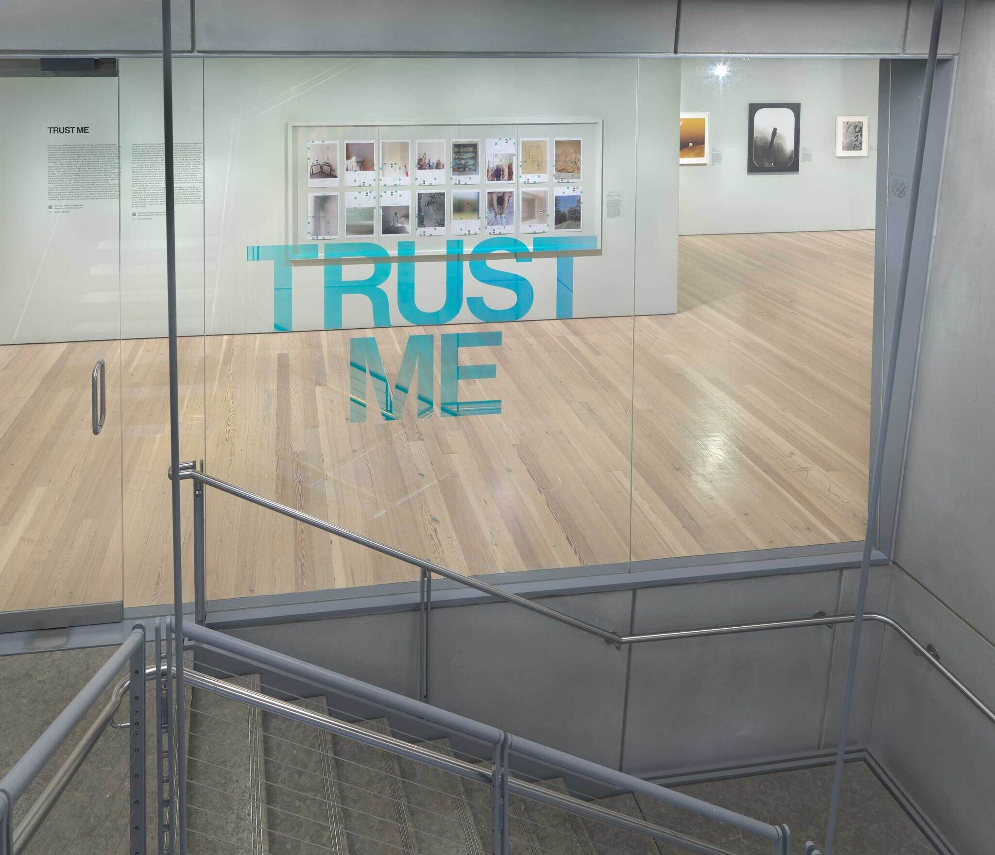 A glass door with the words "Trust Me" in teal and behind the door are various photographs installed.