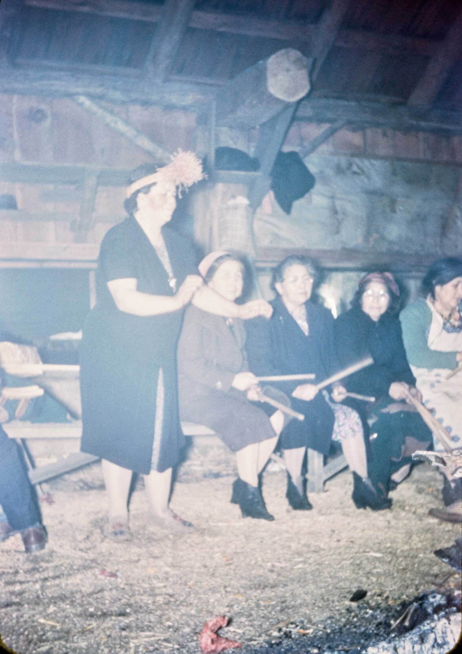 An old slide photograph of four women sitting with instruments and one woman dancing.