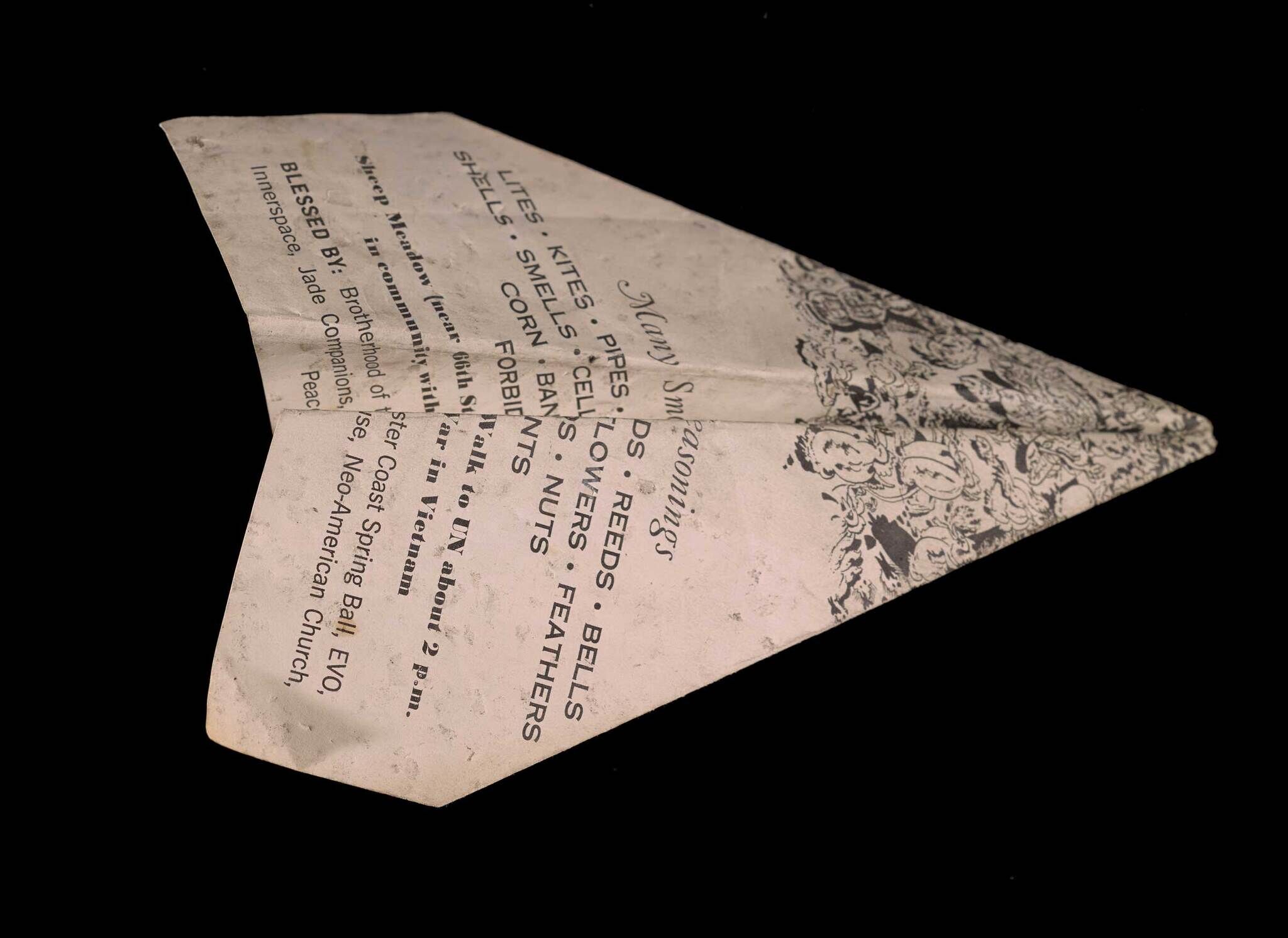 A sheet of white paper with black ink writing and drawings on it that has been folded into a paper airplane