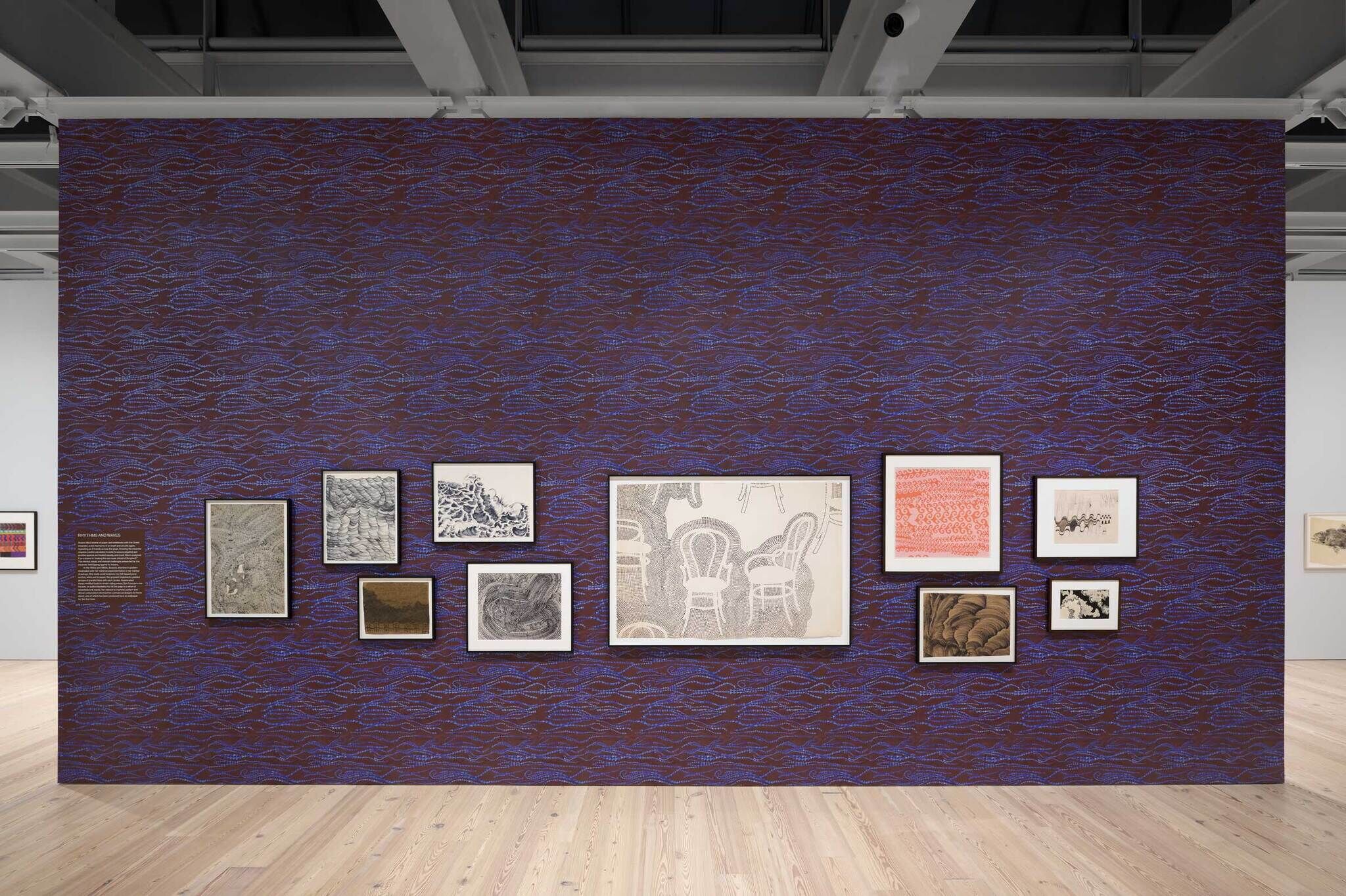 A wall with a brown and purple background with various framed drawings.