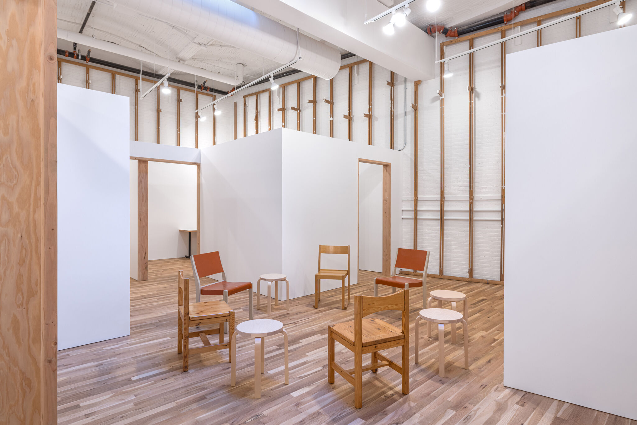 Artist studios and common space in a room with wooden floors and white walls. 