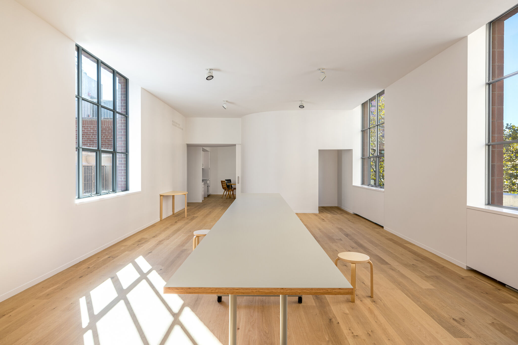 A long table in a bright room with wood floors. 