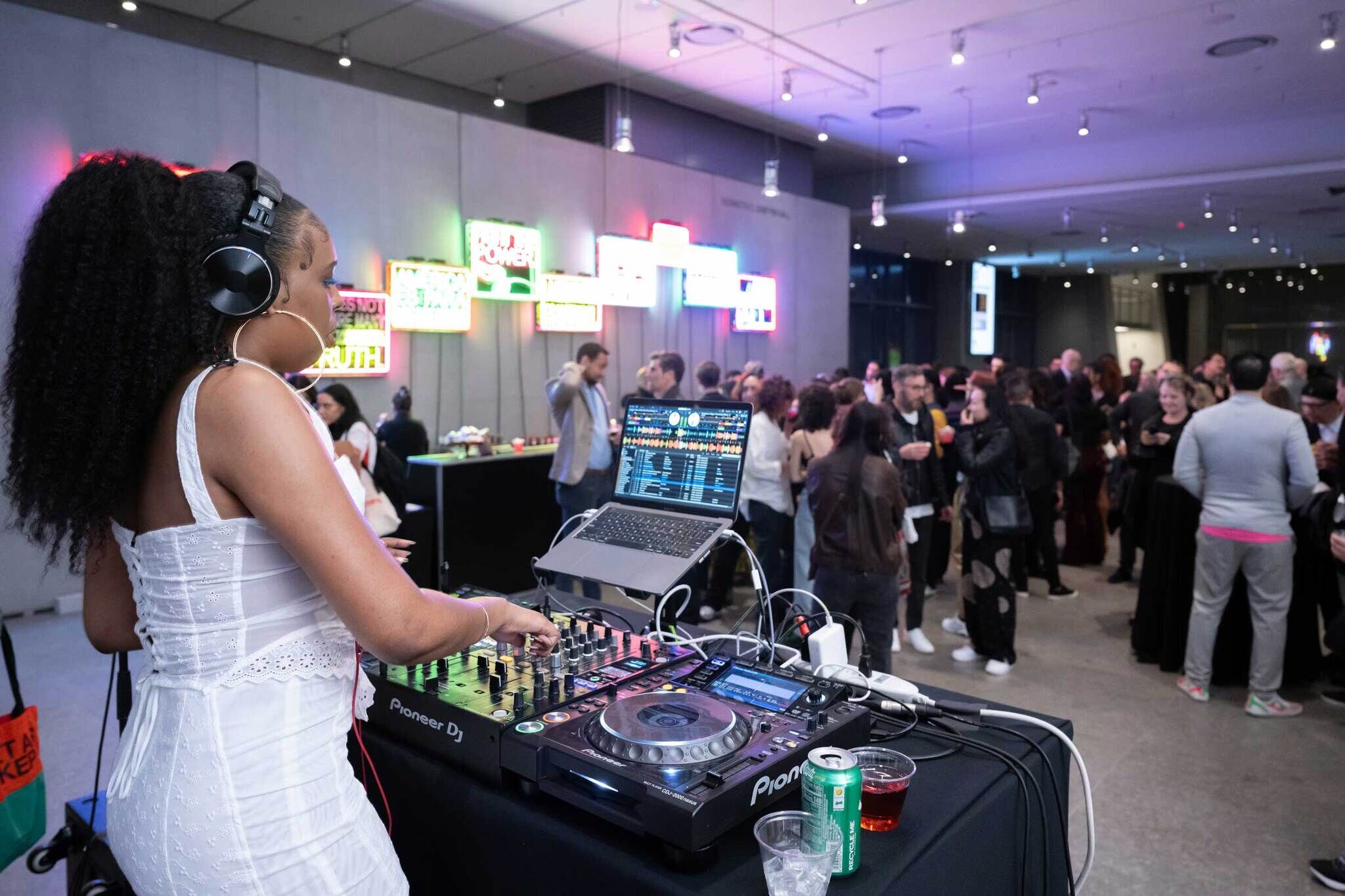 DJ Bembona playing a set in the Whitney Museum Lobby, with guests on the dance floor.
