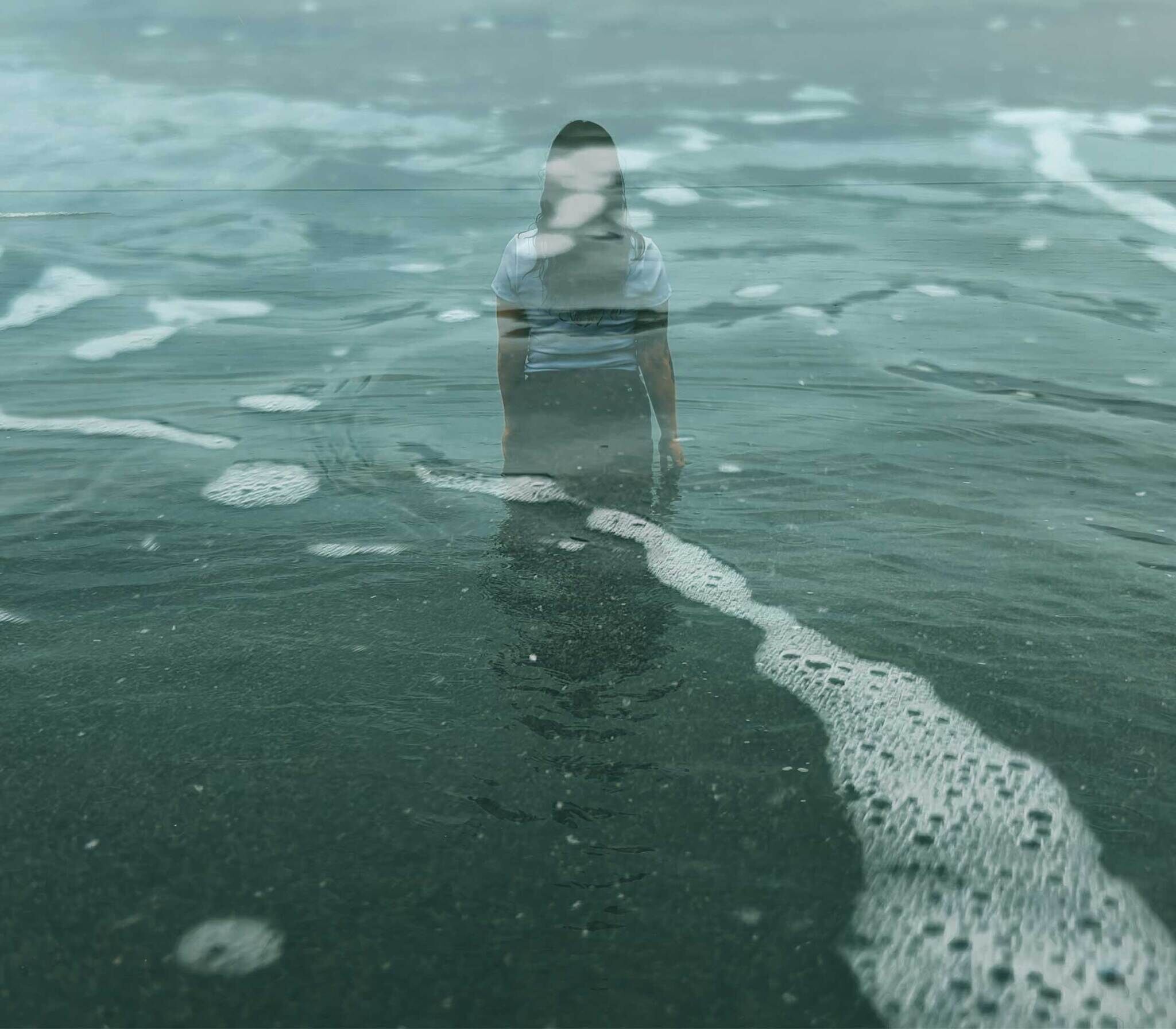 Person standing in shallow water with a reflection on the surface, creating a serene and mysterious atmosphere.