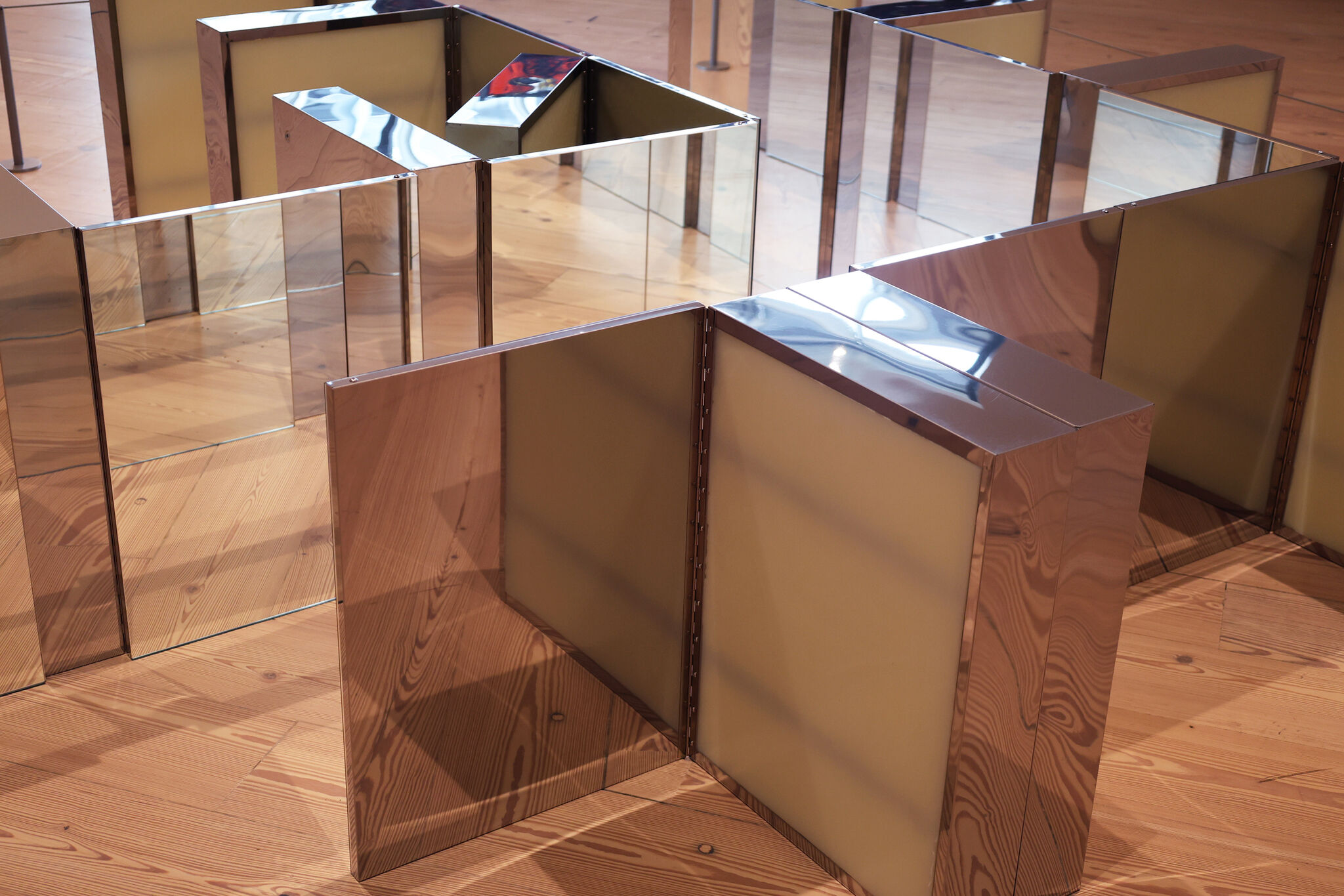 Medicine cabinets placed on the ground and forming geometric shapes obscured by mirrors. 