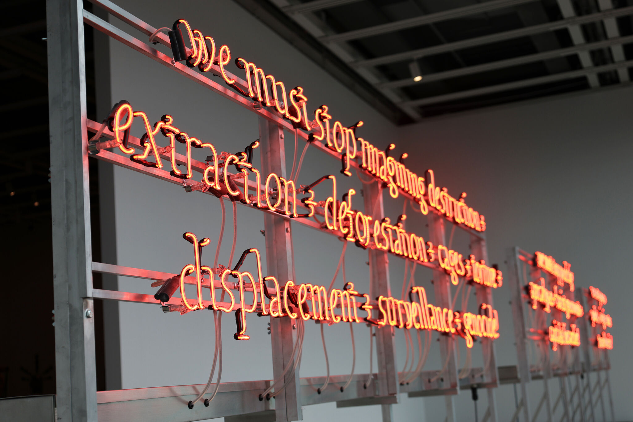 Neon light installation with words against a gallery wall.