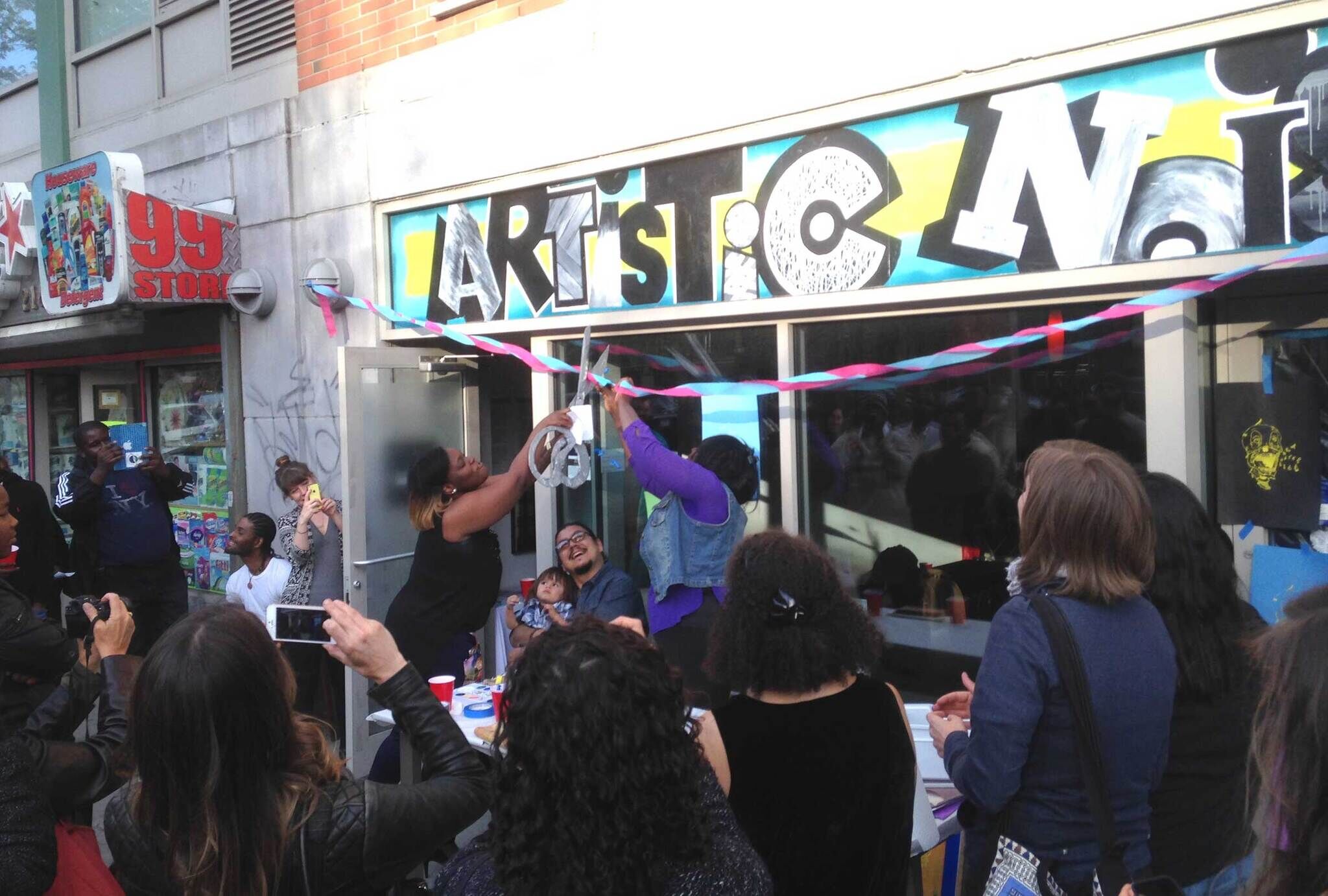People celebrating outside a store cutting a ceremonial ribbon.