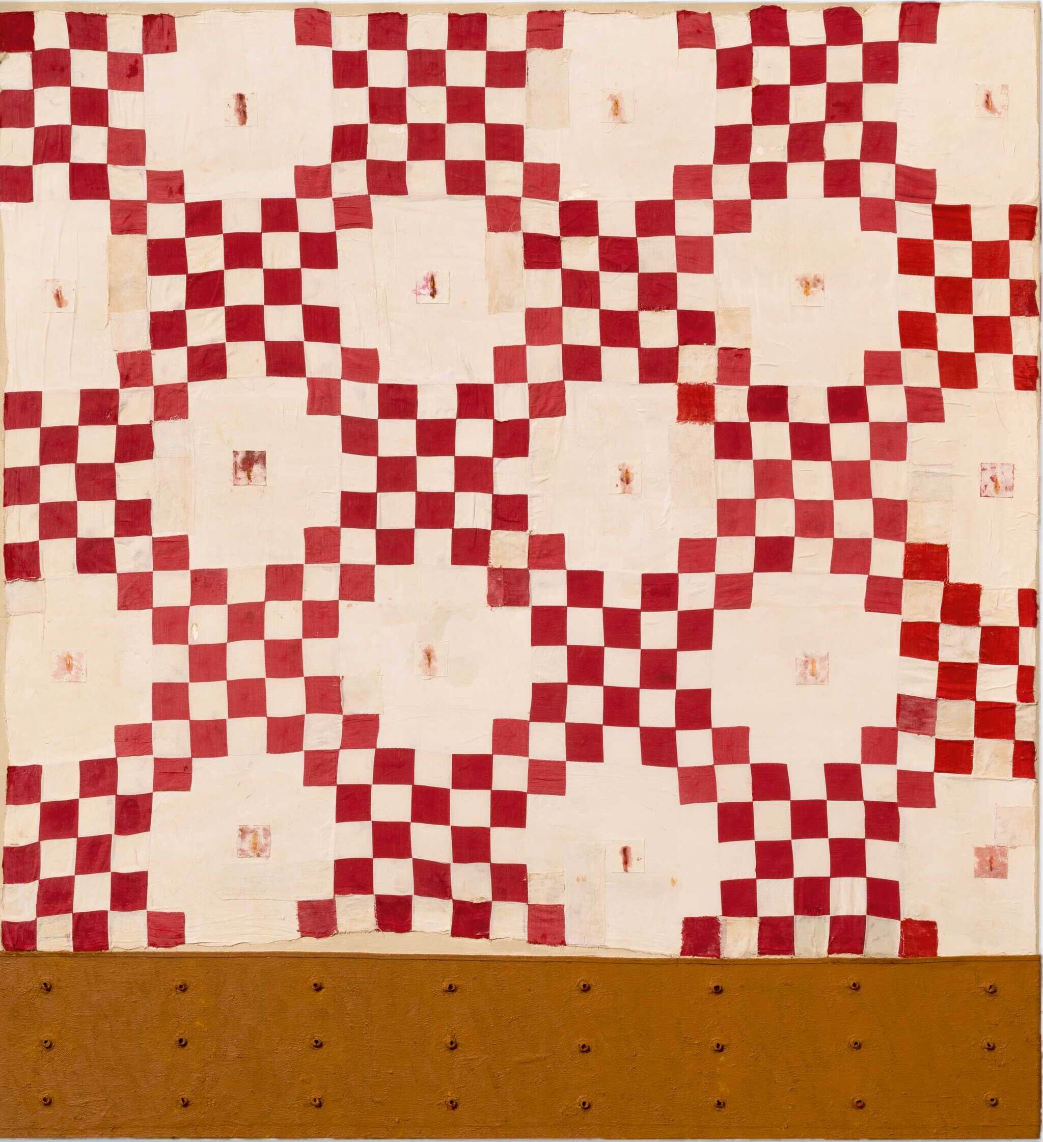 A stained red and white checkered quilt with a repeating pattern.
