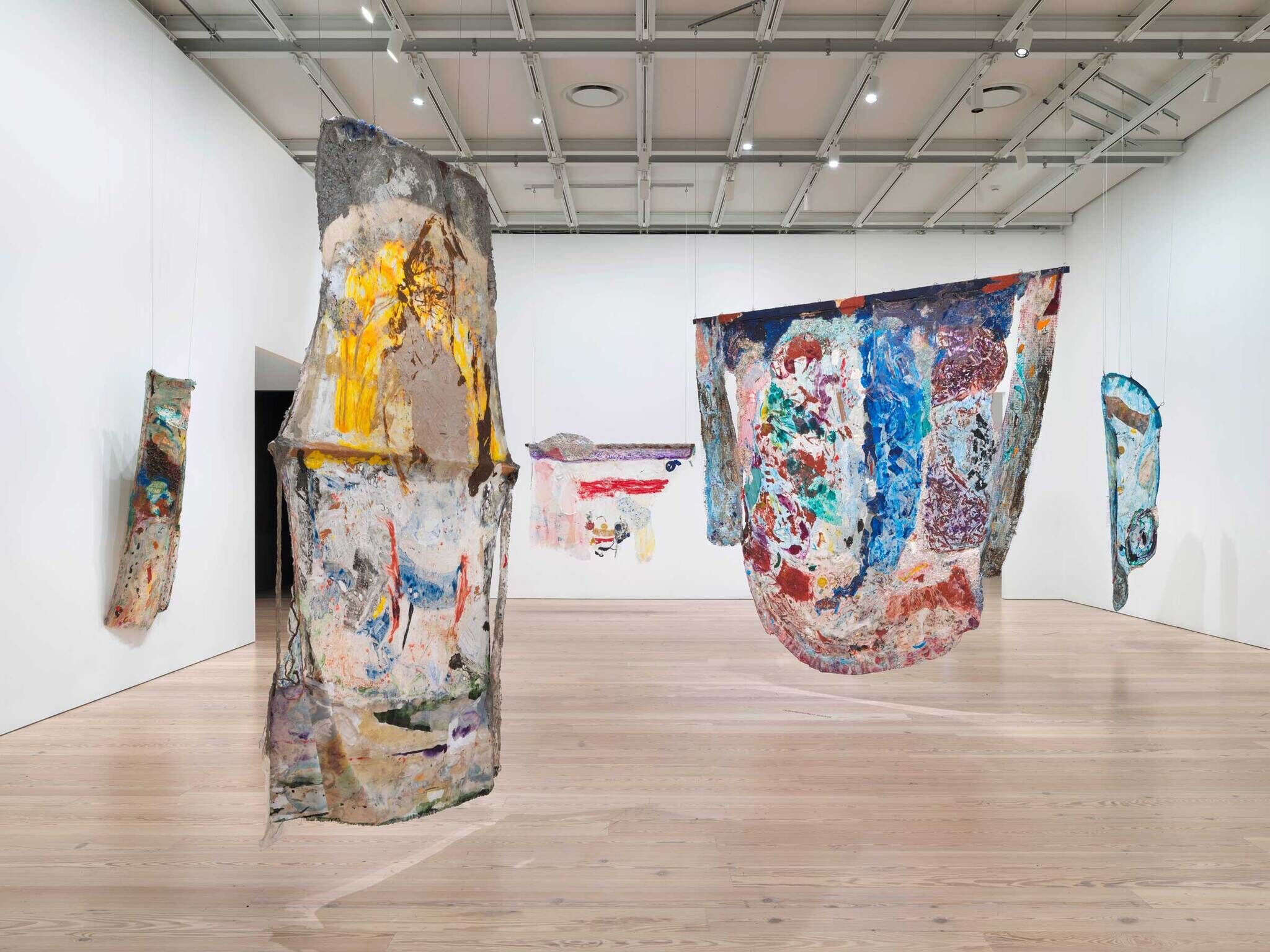 Abstract painted sculptures suspended in a modern art gallery setting.