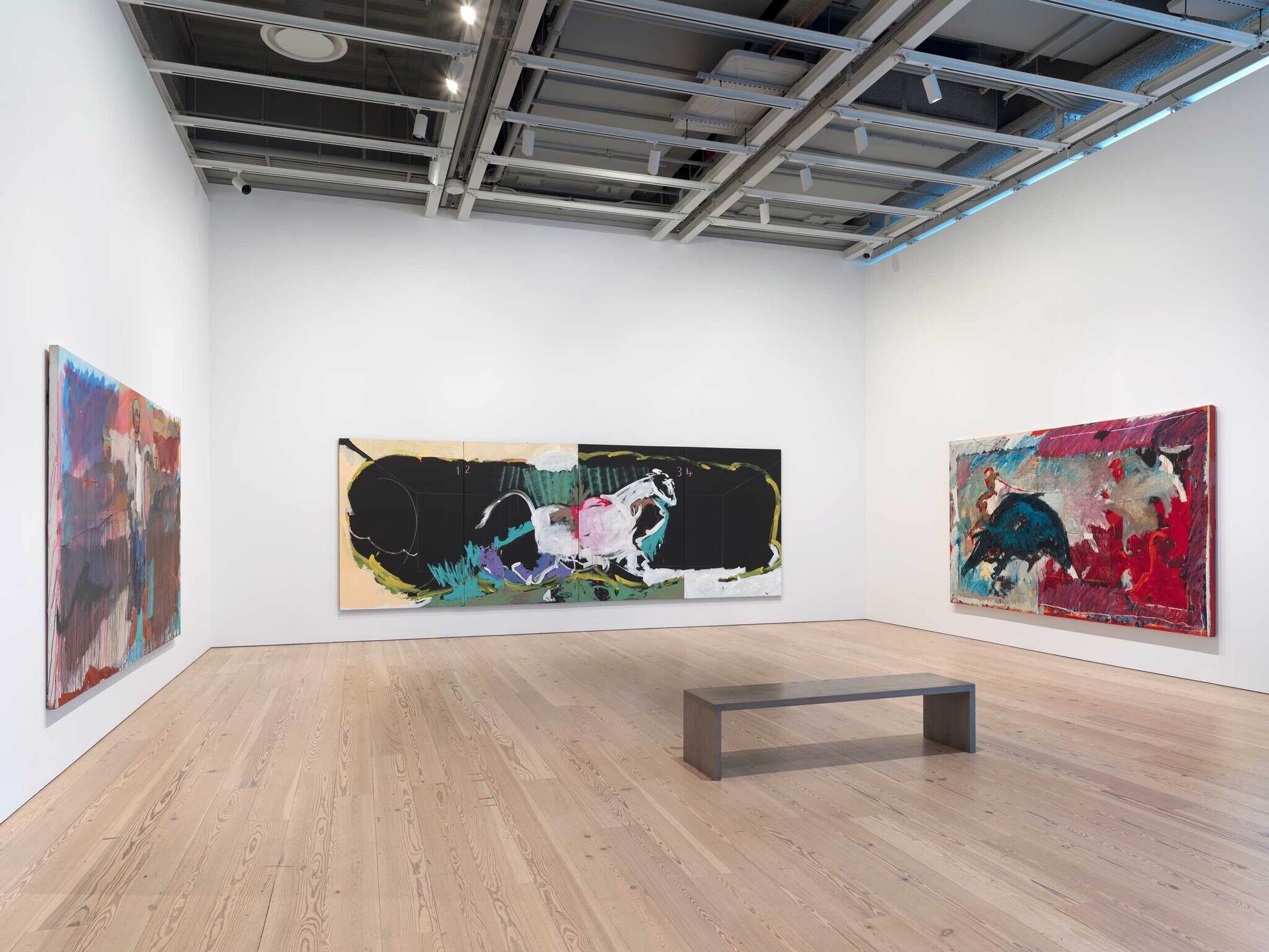 Modern art gallery interior with three large abstract paintings on white walls and a wooden floor, with a bench in the center.