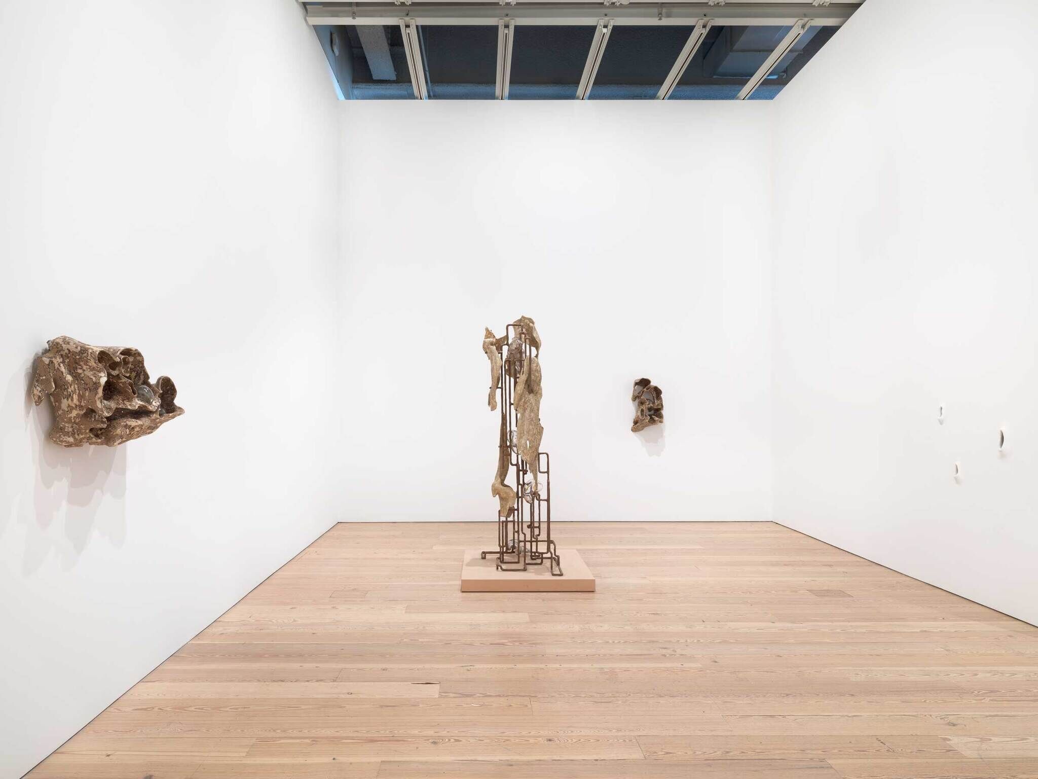 Modern art gallery interior with abstract sculptures on white walls and wooden flooring.