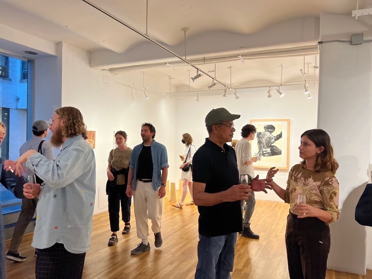 People conversing at an art gallery with paintings on the walls.