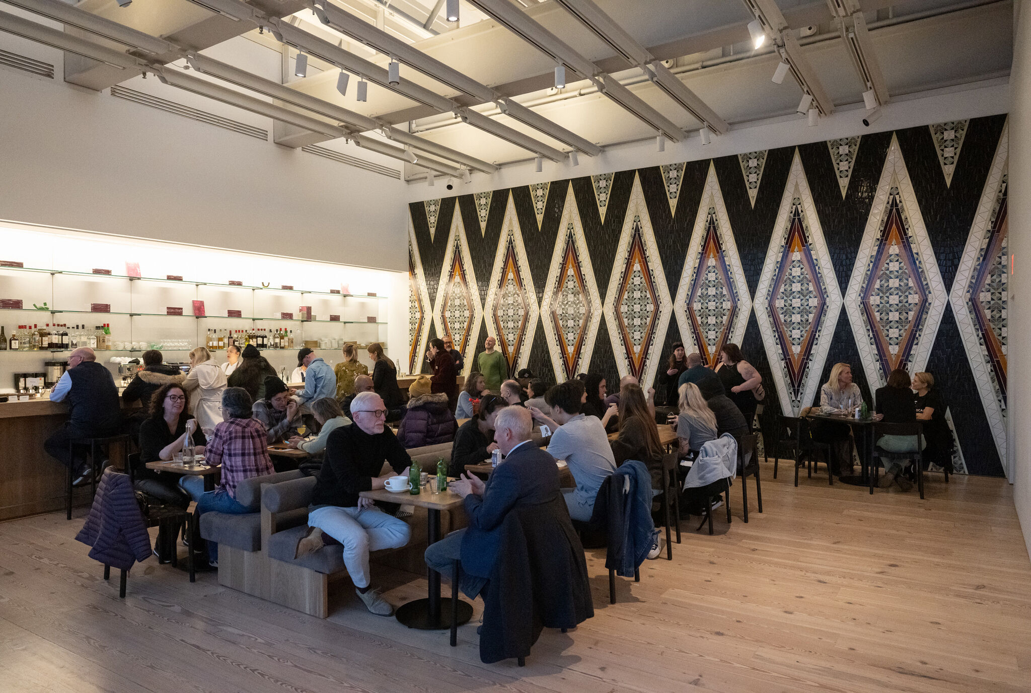 People socializing in a modern cafe in front of a geometric artwork.