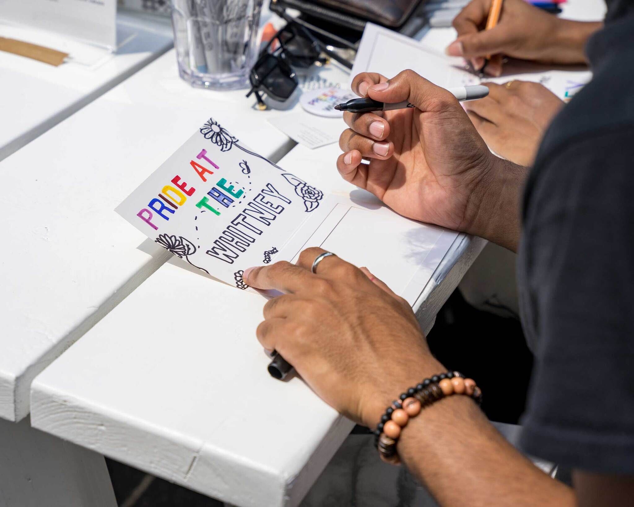 Tight cropped photo of hands making artwork with text that reads 'Whitney Pride'