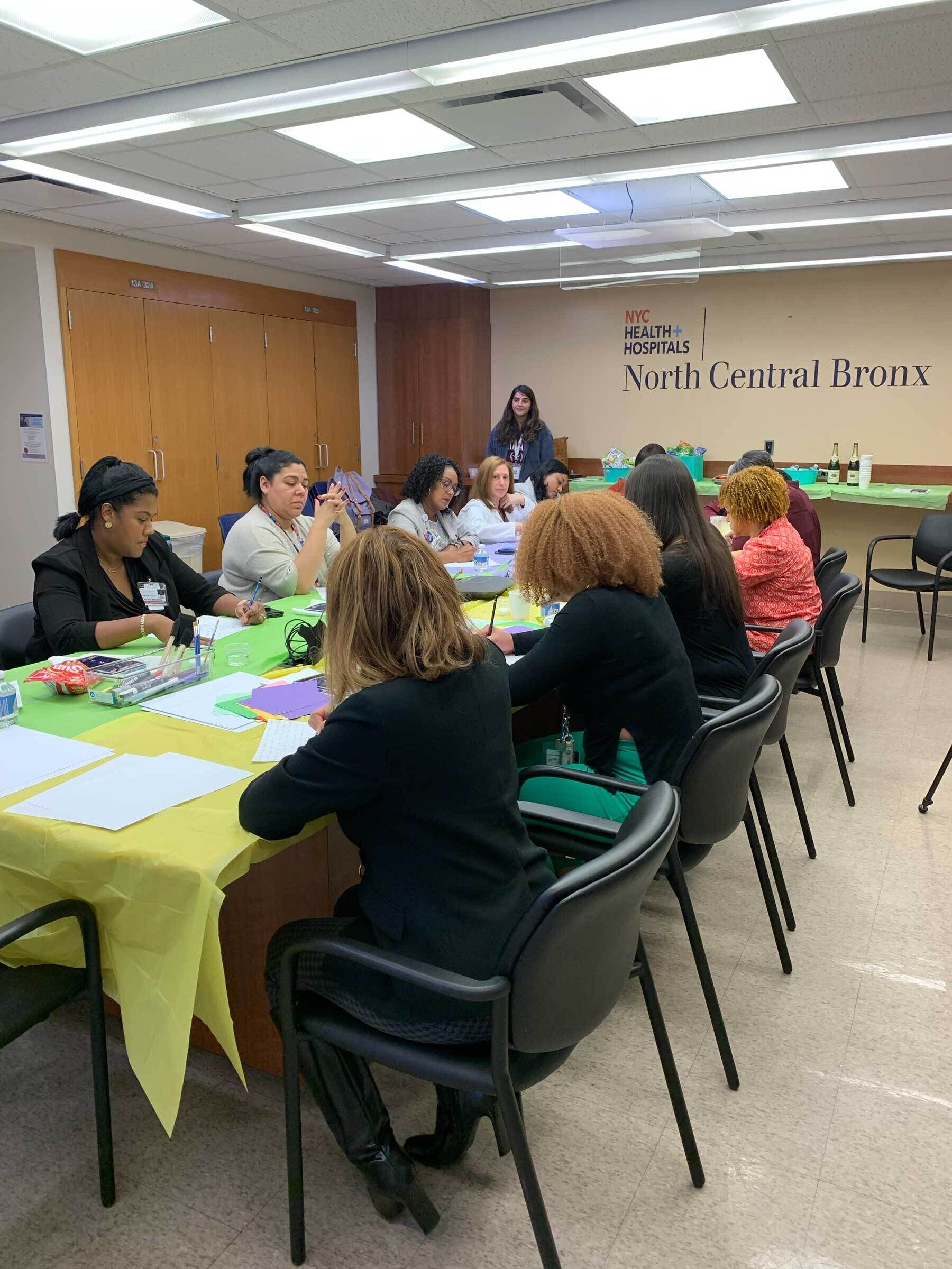 Group of professionals in an art session at North Central Bronx Hospital with papers and bottles on the table.