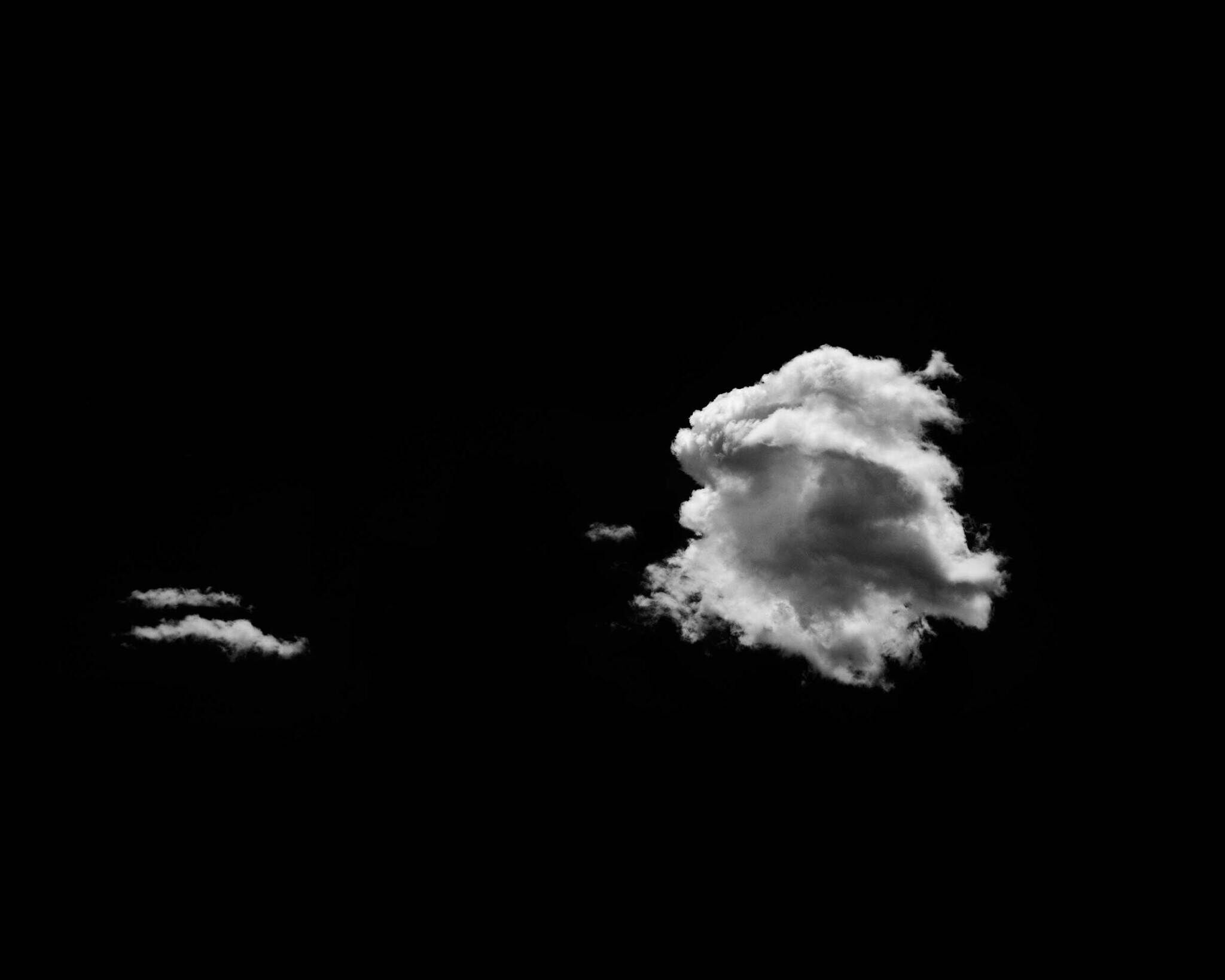 White clouds against a black background, with one large cloud on the right and a smaller one on the left.