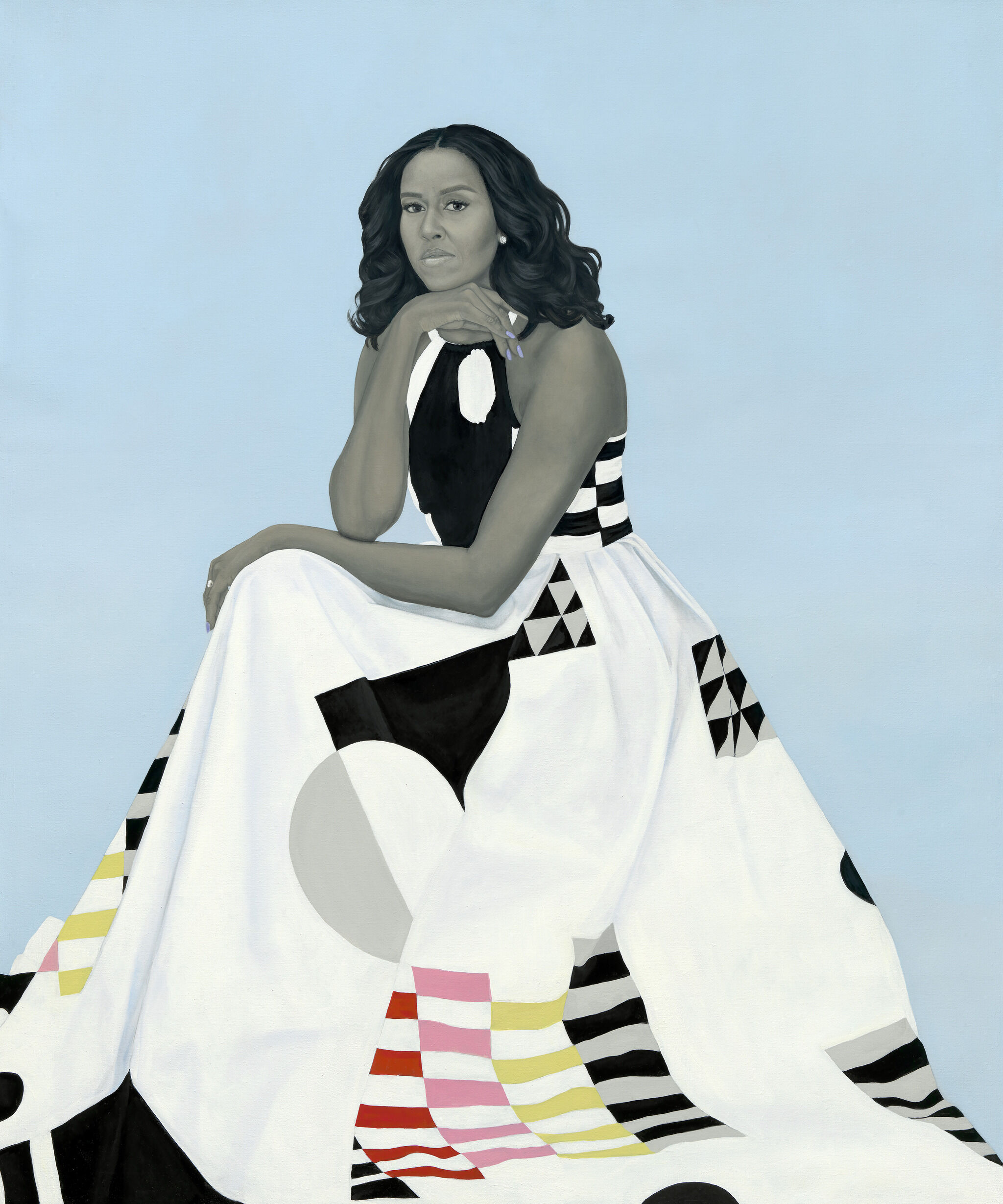 A woman in a patterned dress sits against a light blue background, resting her chin on her hand and looking forward with a calm expression.