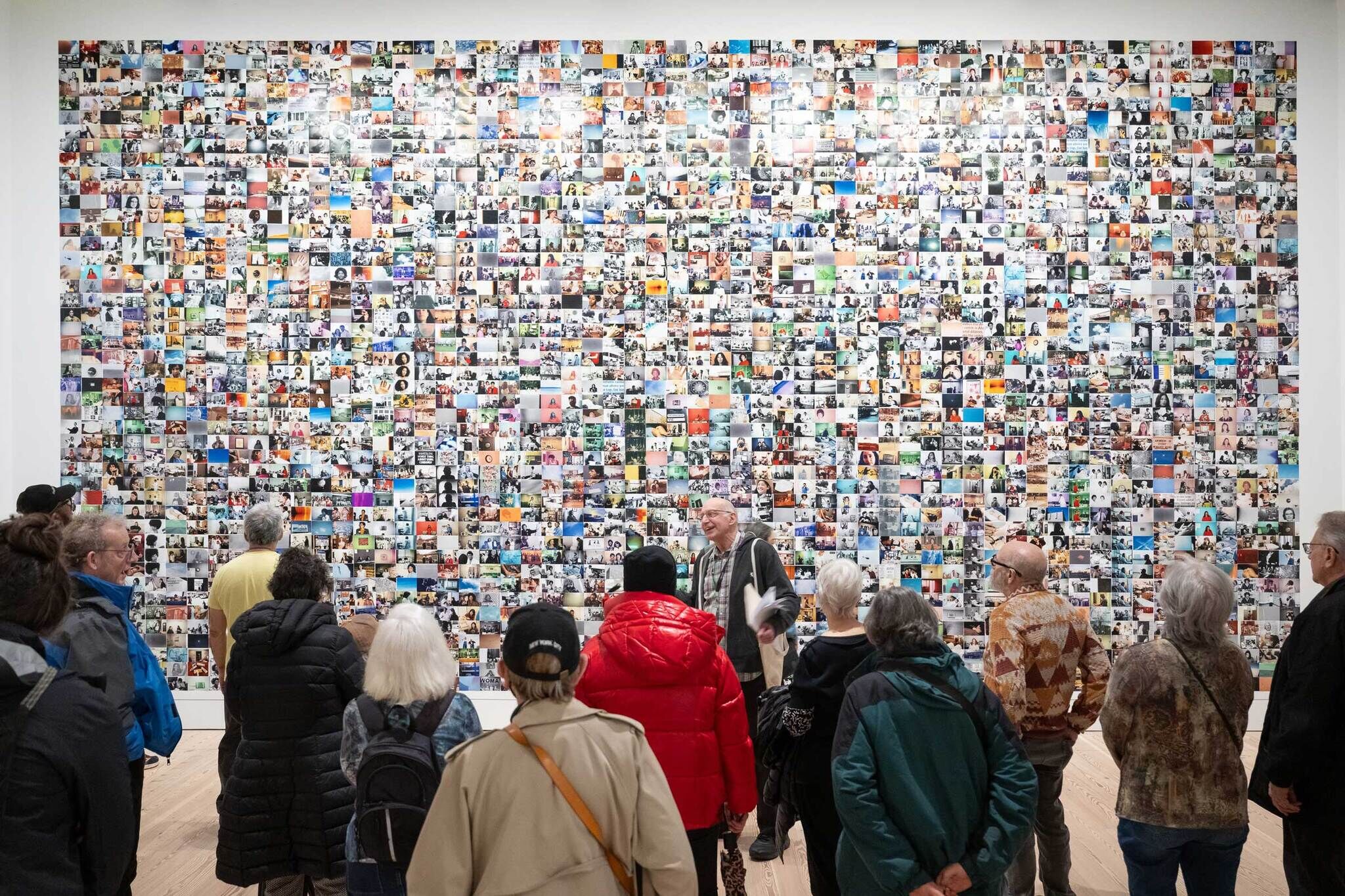 A large group of Older Adults in the Whitney Museum galleries listening to a Senior Open Access Day tour guide